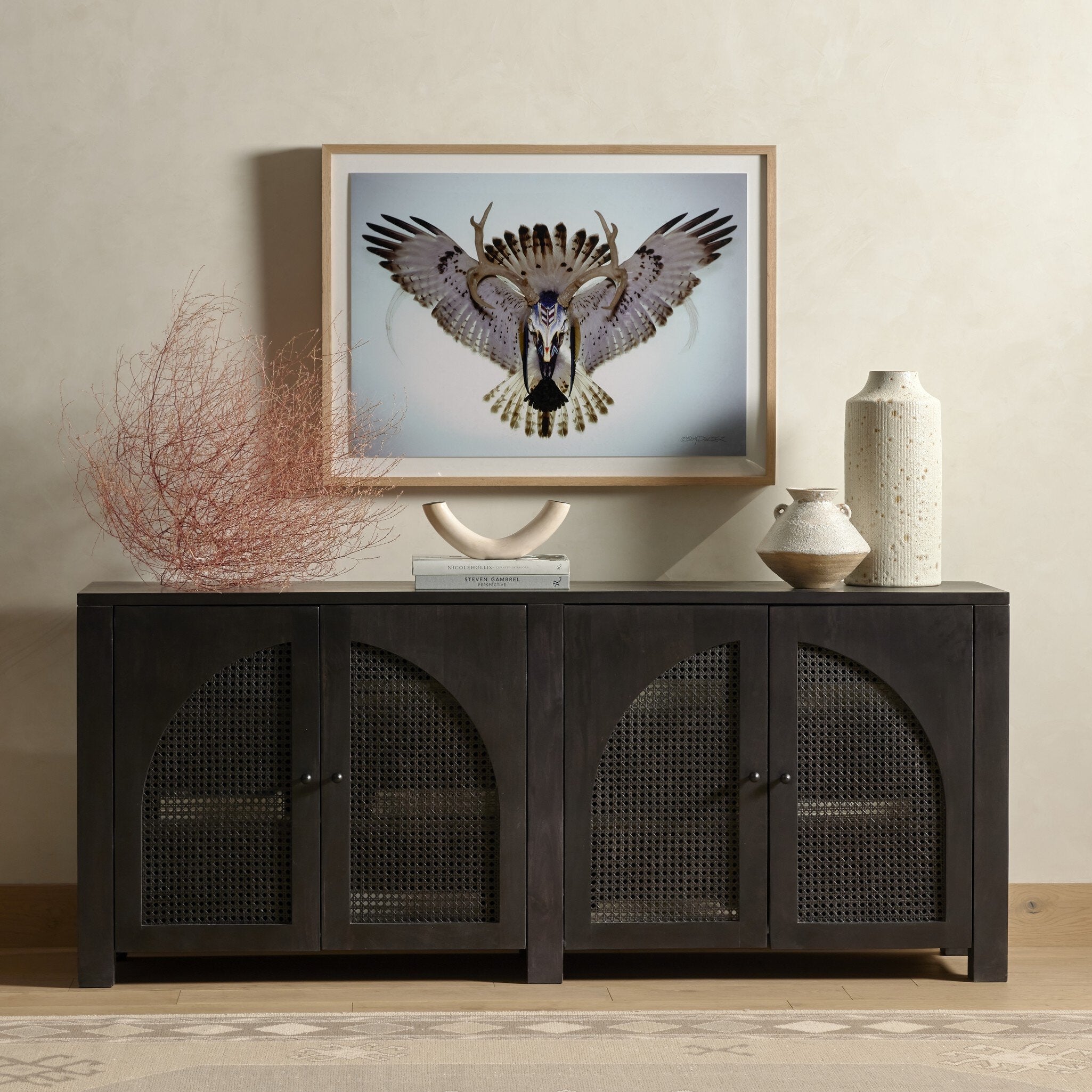 Framed artwork of an eagle above a dark wooden cabinet with decorative items.