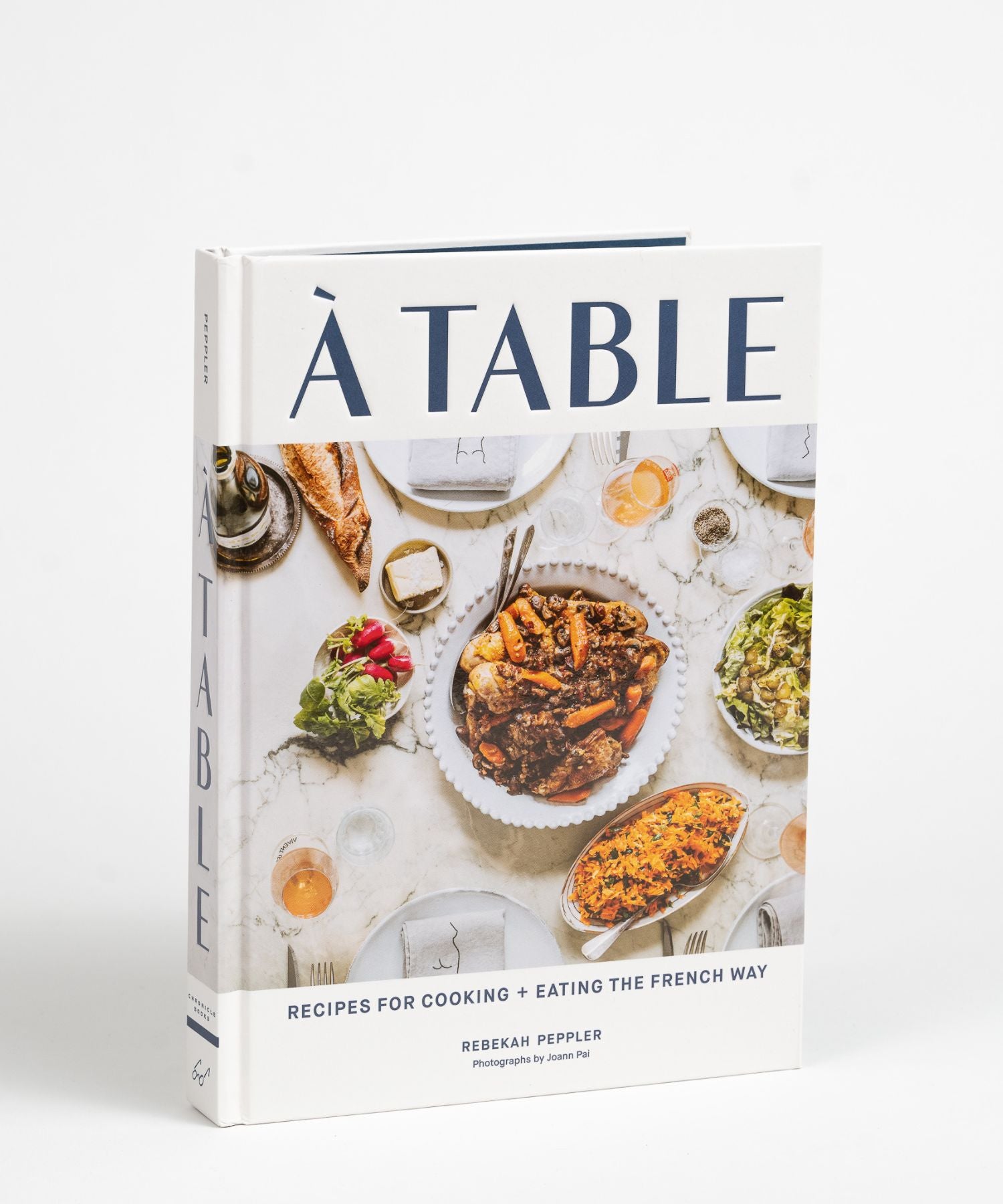 The cover of "À Table" by Rebekah Peppler features a French meal with dishes like roast chicken, carrots, salad, red wine, and bread on a marble table.