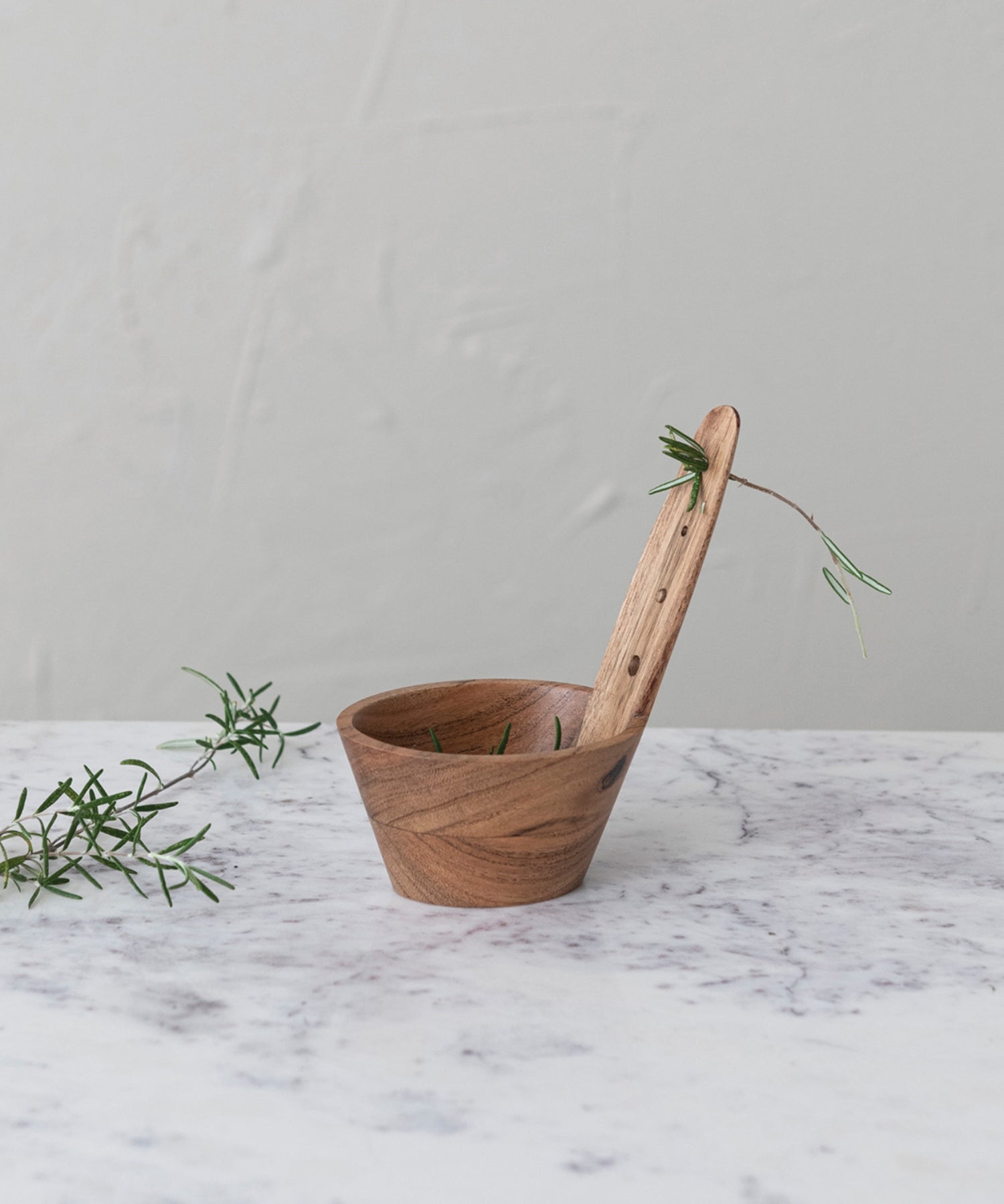A natural Acacia wood herb stripper featuring a cylindrical bowl and a paddle-like handle with holes. The wood grain is prominent, conveying a rustic, hand-crafted feel. | Wildwood Home Co.