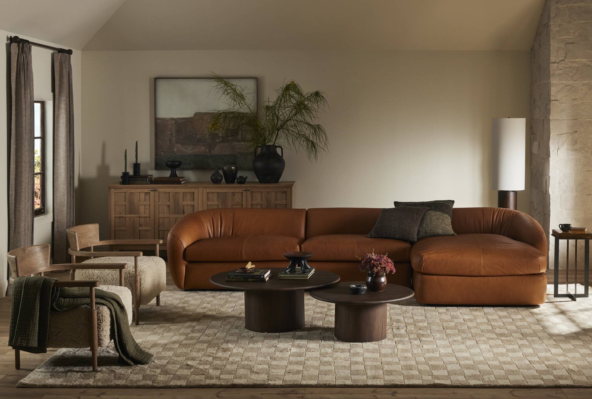 Cozy living room with a brown leather sectional sofa, wooden sideboard, coffee table, and decorative items.