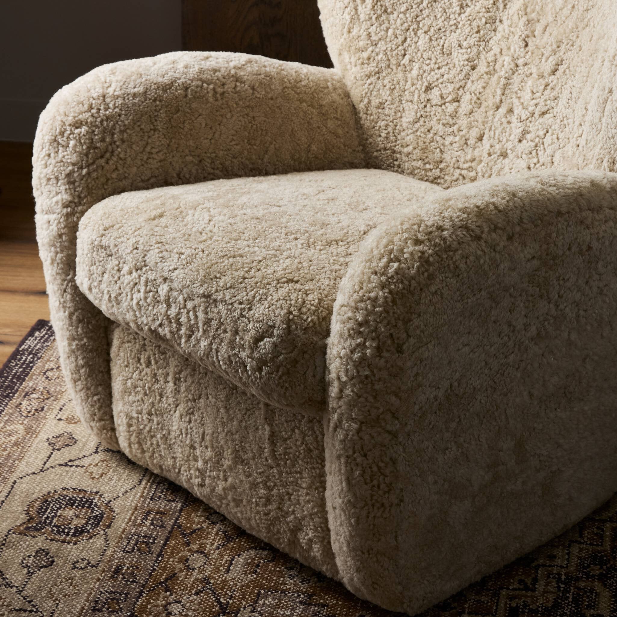 Close-up of a textured beige armchair on a patterned rug.