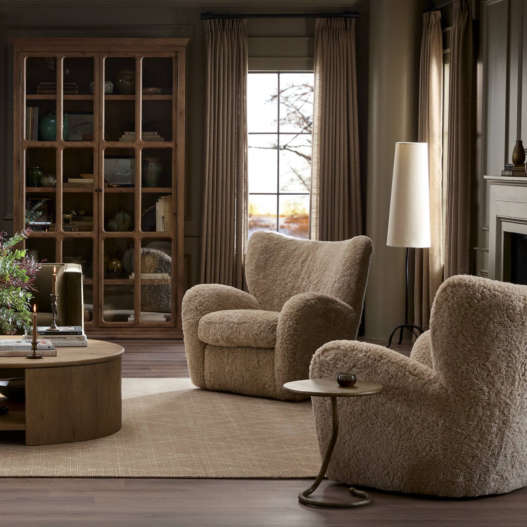 Cozy living room with two beige armchairs, a round wooden table, and a bookshelf. | Wildwood Home Co.