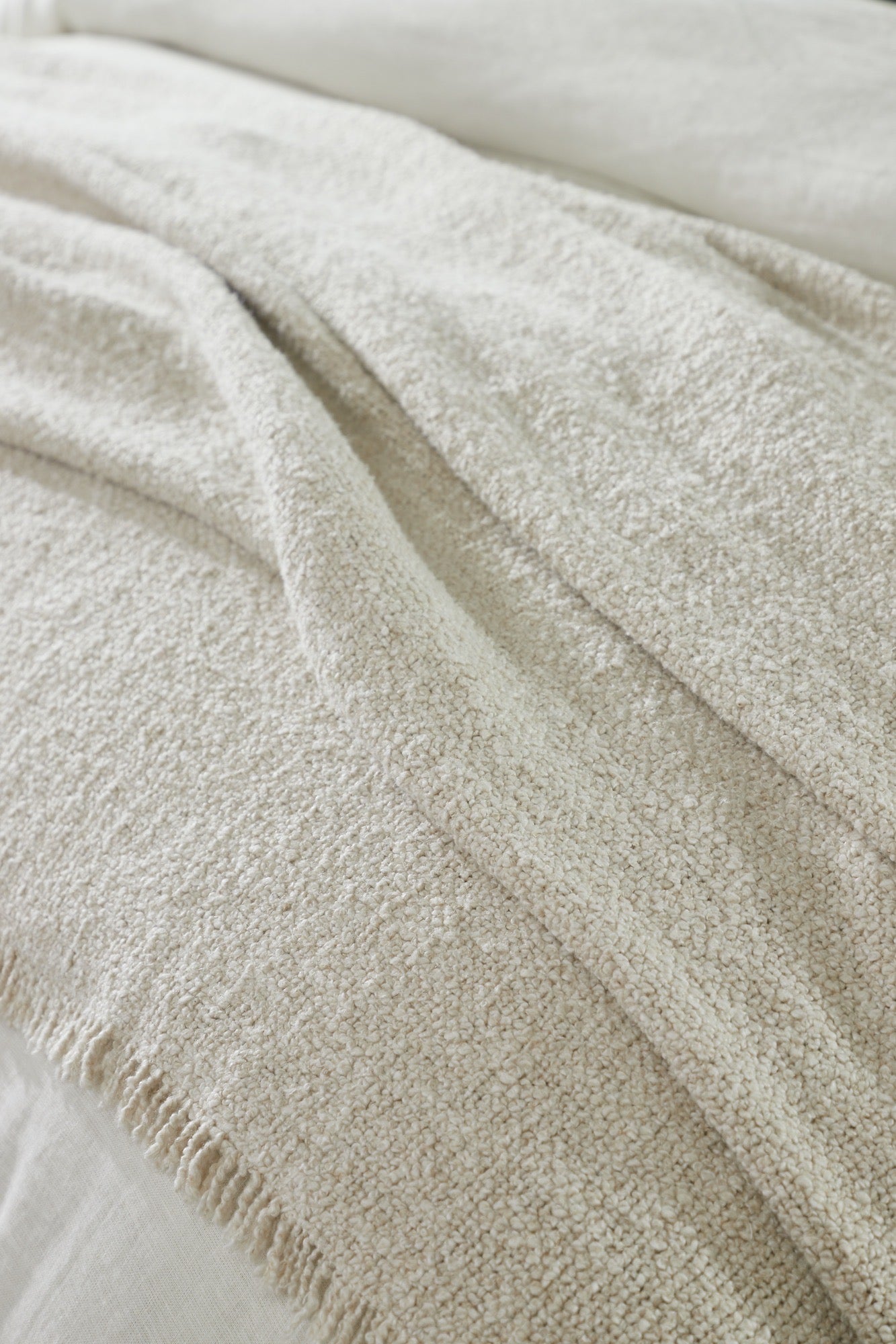 Stacked cream coverlet and shams showcasing their boucle weave and natural softness. | Wildwood Home Co.