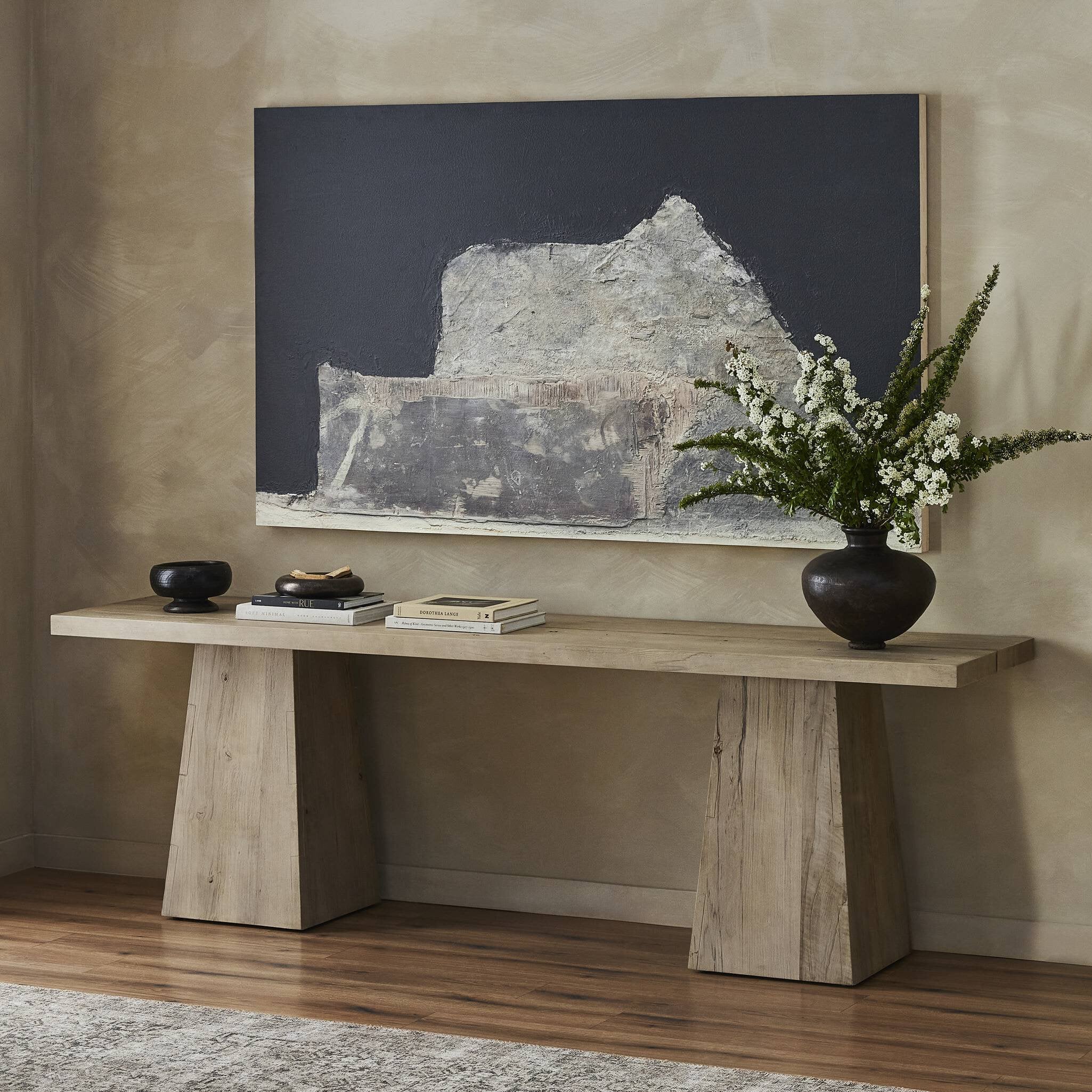 Wooden console table with decorative items against a wall with a large abstract painting. | Wildwood Home Co.