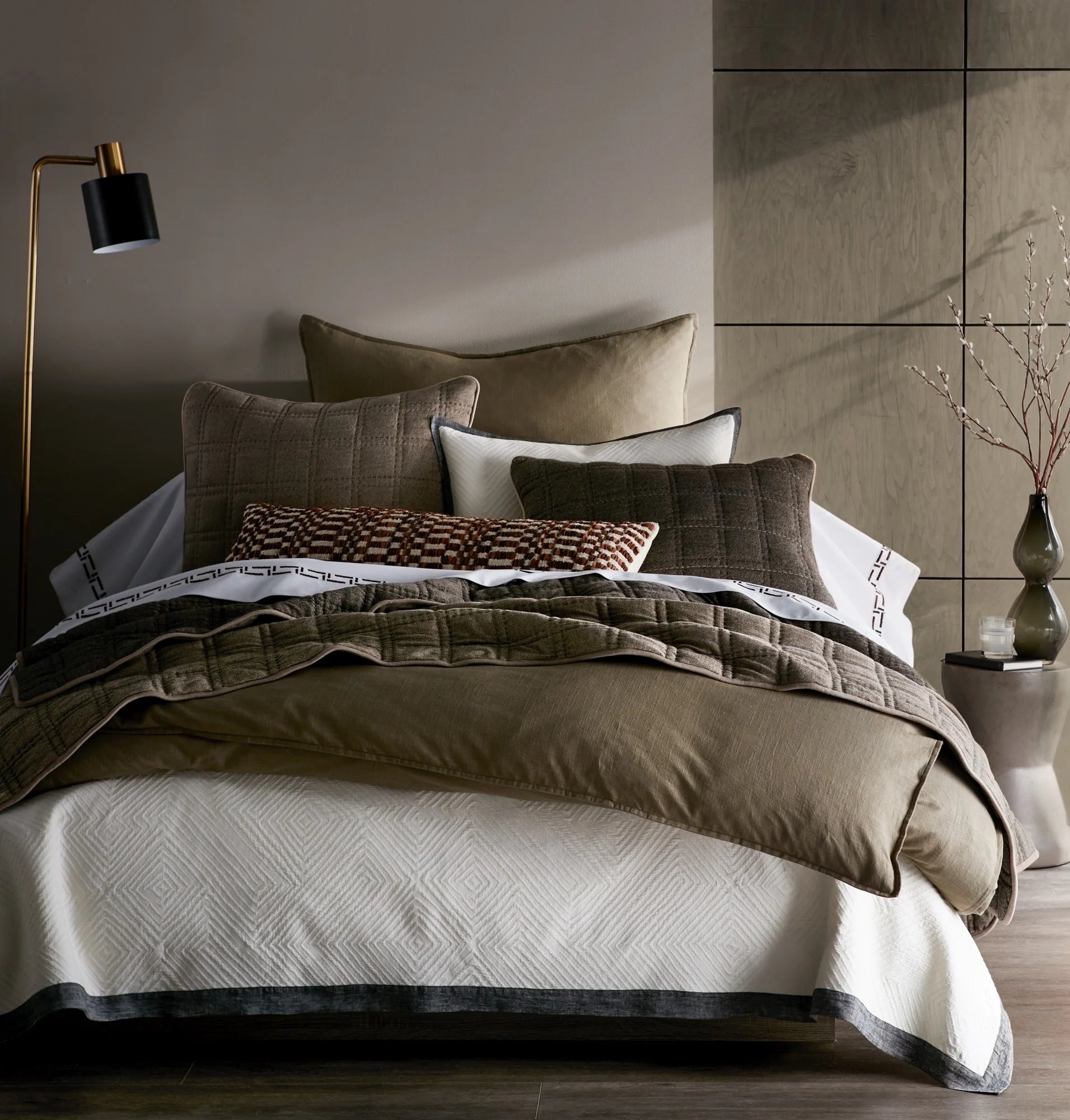 Bed with neutral brown linen bedding and pillows in a modern bedroom setting.
