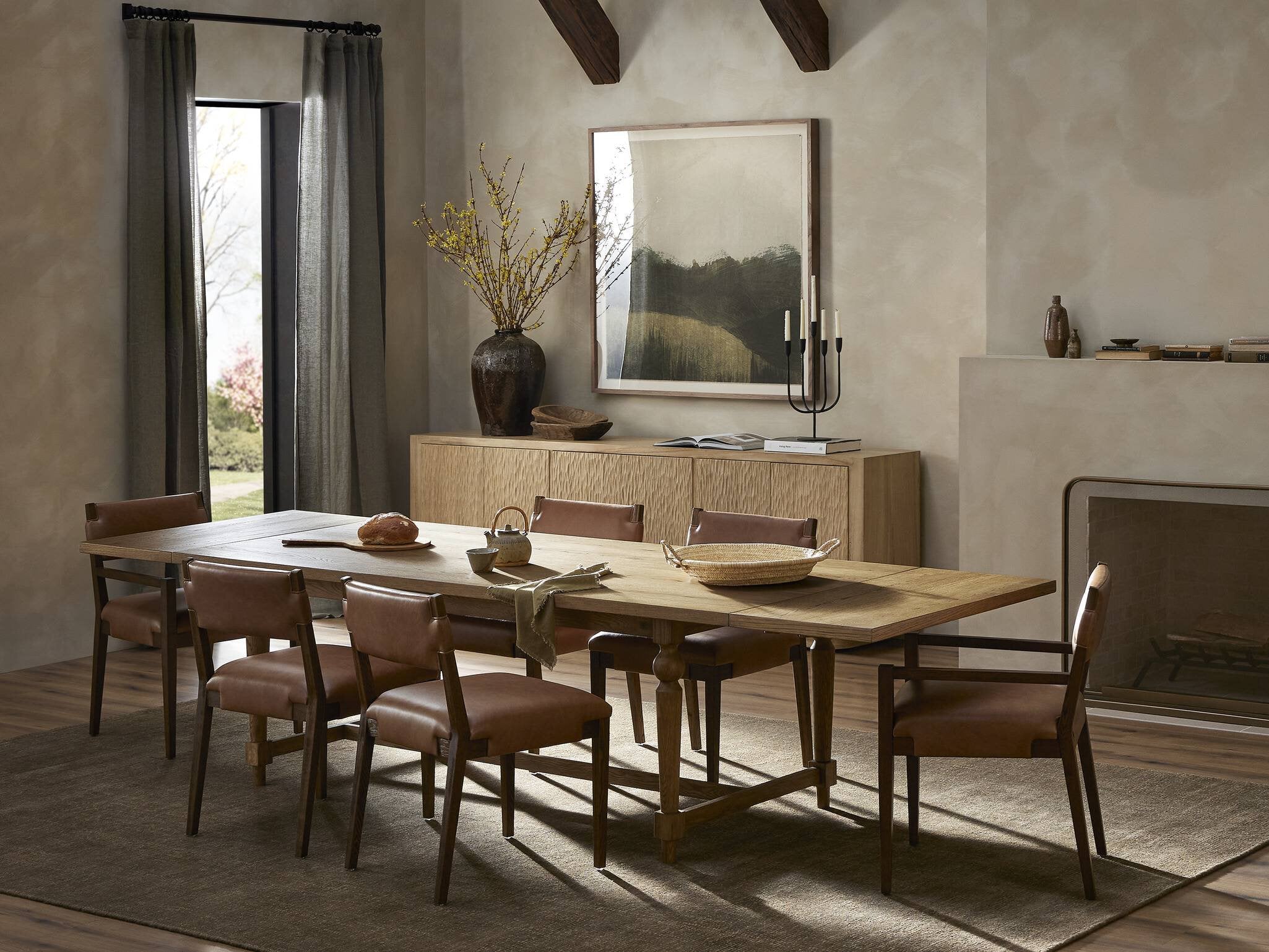 Dining room with wooden table and chairs, large mirror on the wall, and fireplace. | Wildwood Home Co.