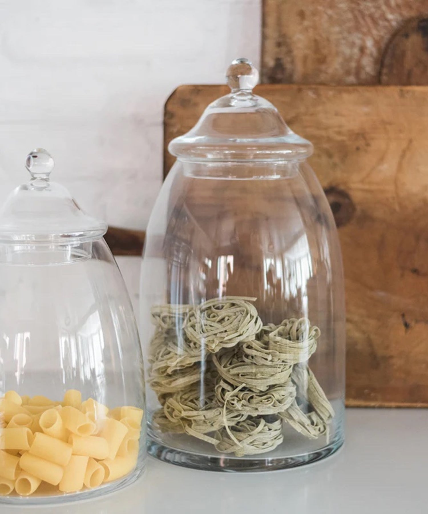 Two clear glass apothecary jars with a domed lid and rounded knob. Each styled with pasta. | Wildwood Home Co.