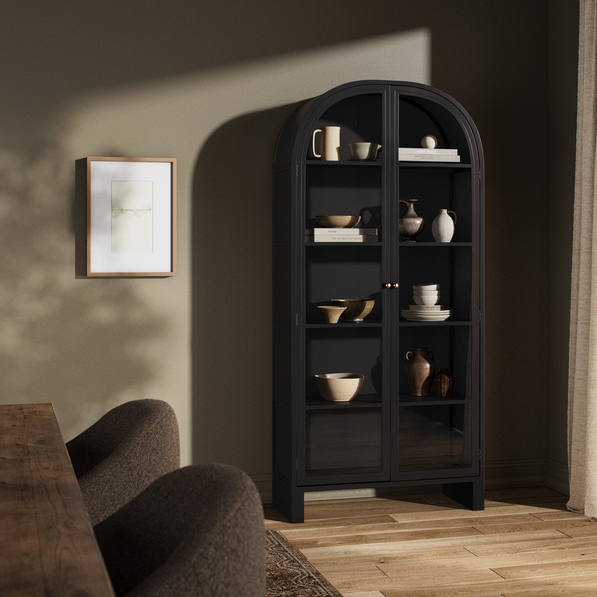 Black-finished iron arched cabinet with decorative items in a room with a sofa and framed picture. | Wildwood Home Co.