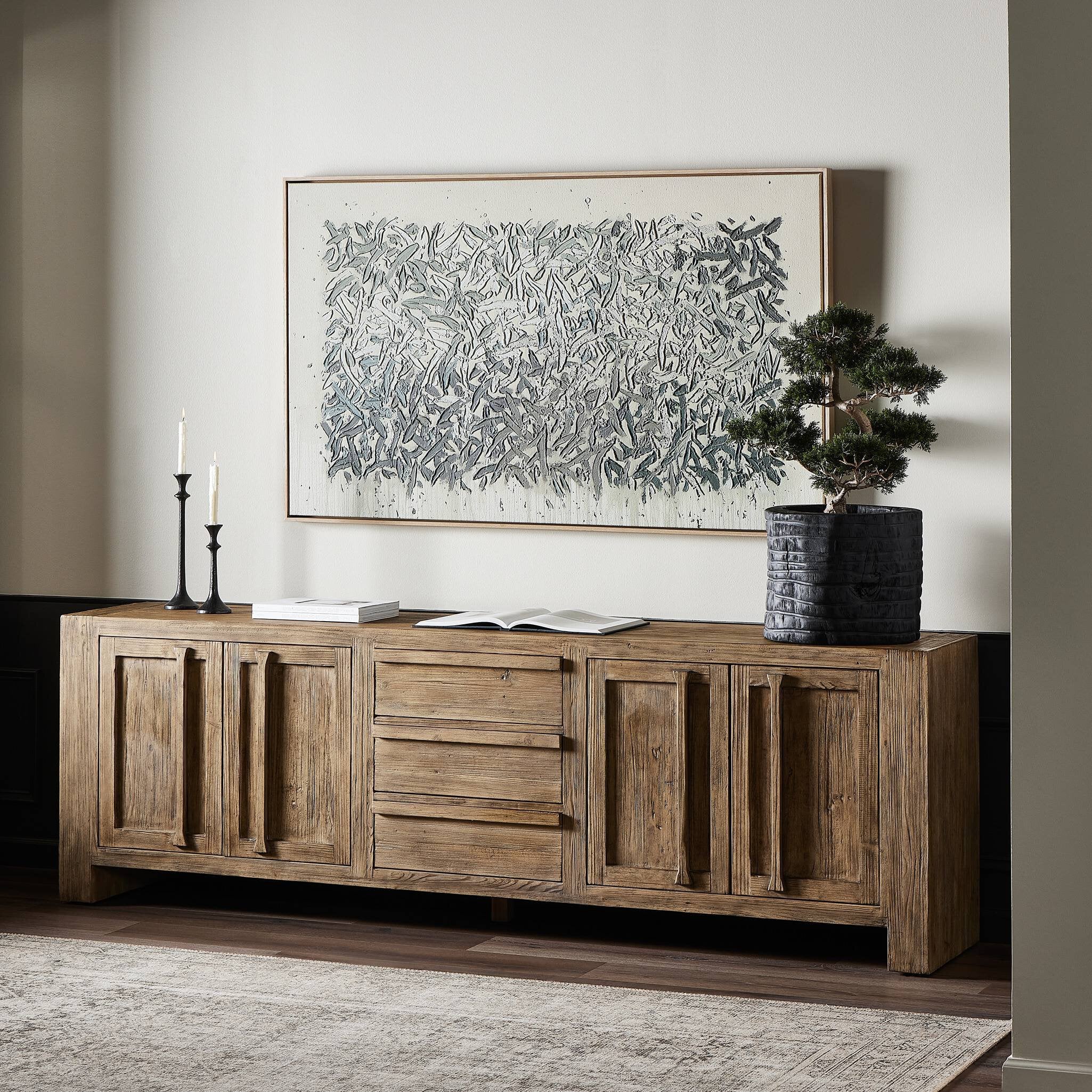 Wooden sideboard in a room with a large abstract painting on the wall. | Wildwood Home Co.