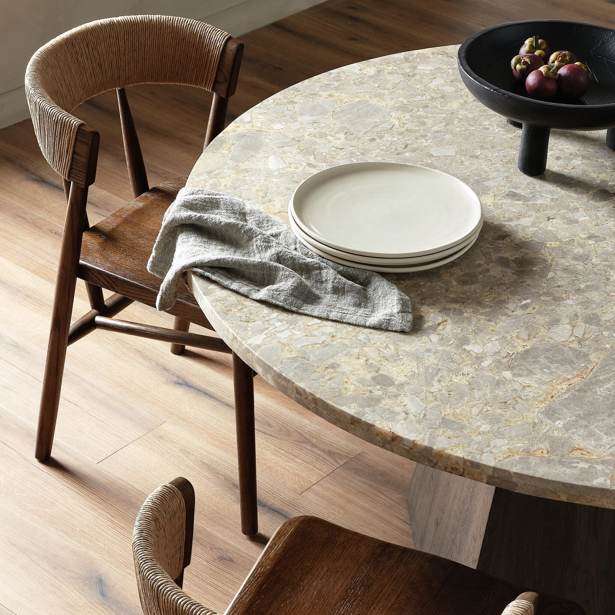 Round stone table with wooden chairs in a dining setting. | Wildwood Home Co.
