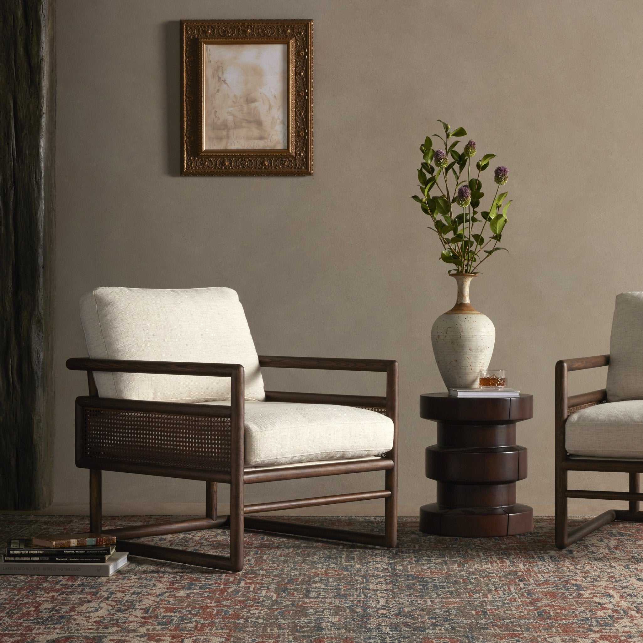 Two armchairs in a room with a framed picture and a vase on a small table. | Wildwood Home Co.
