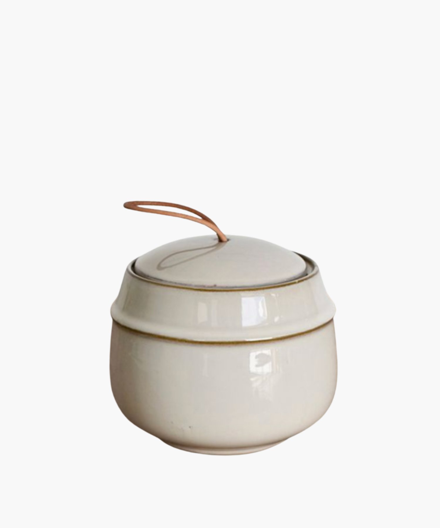 Elegant cream-colored ceramic jar with a lid, featuring a simple, rustic design. A leather loop handle adds a touch of warmth and charm. | Wildwood Home Co.