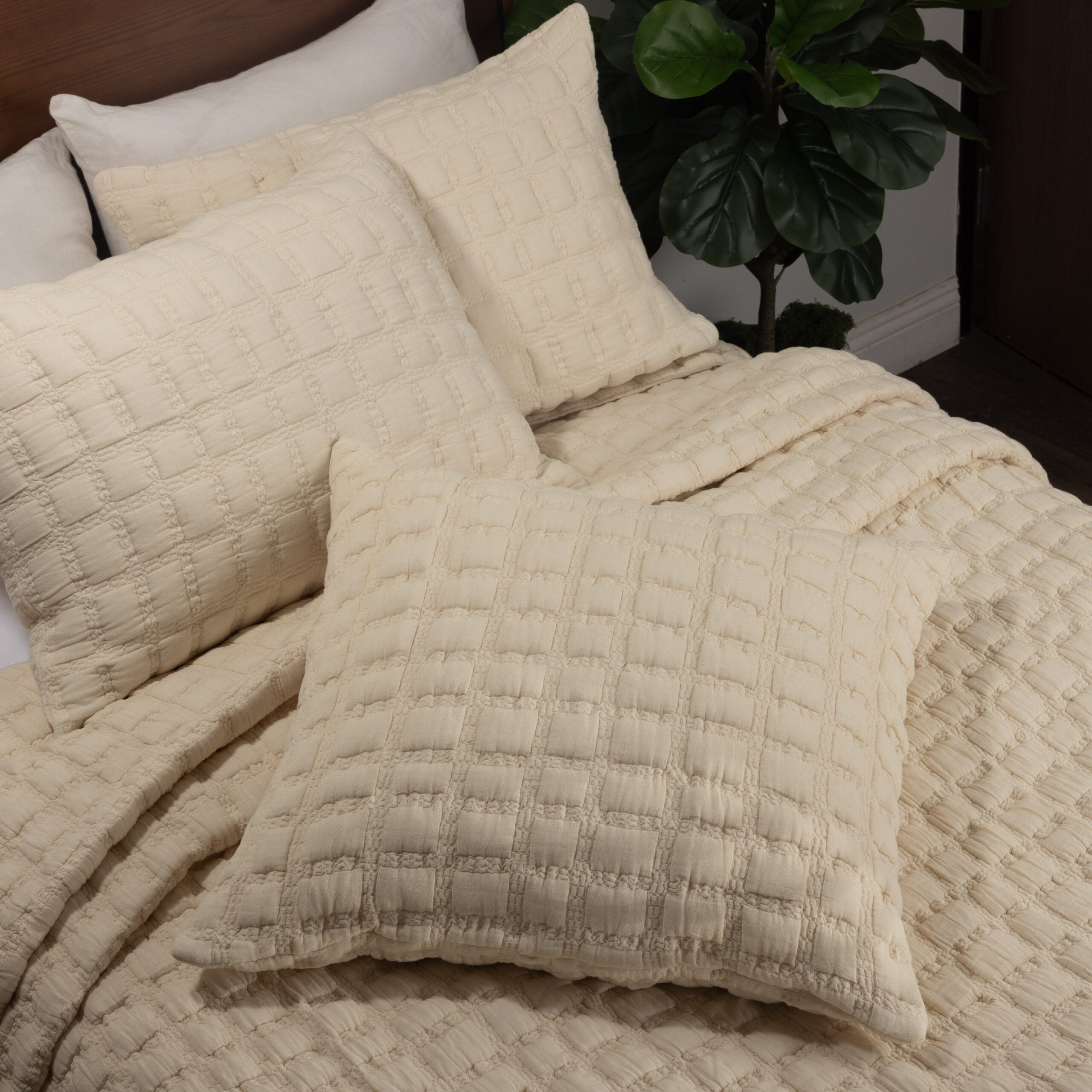 Cream quilt and matching shams layered on a bed, highlighting the plush grid texture and soft cotton finish. | Wildwood Home Co.