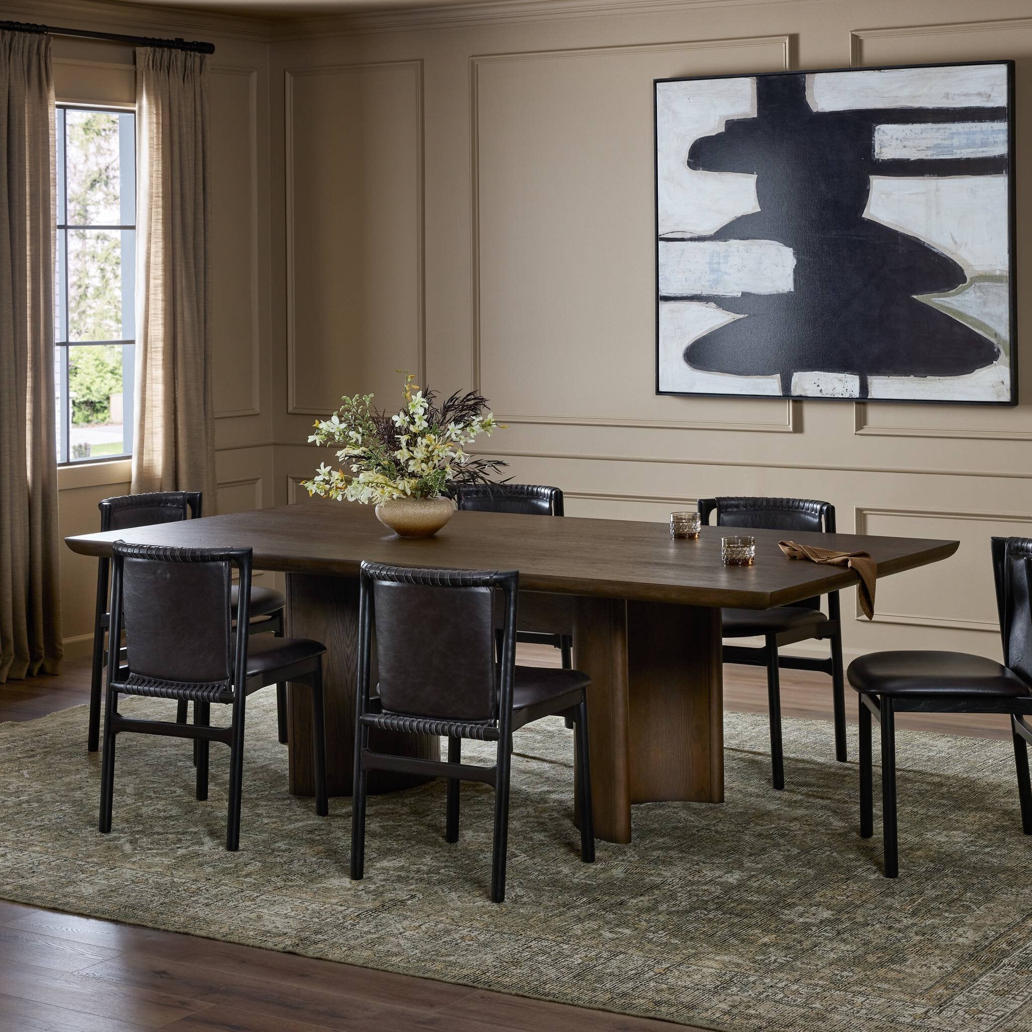 Dining room with wooden table and black chairs, abstract painting on the wall. | Wildwood Home Co.