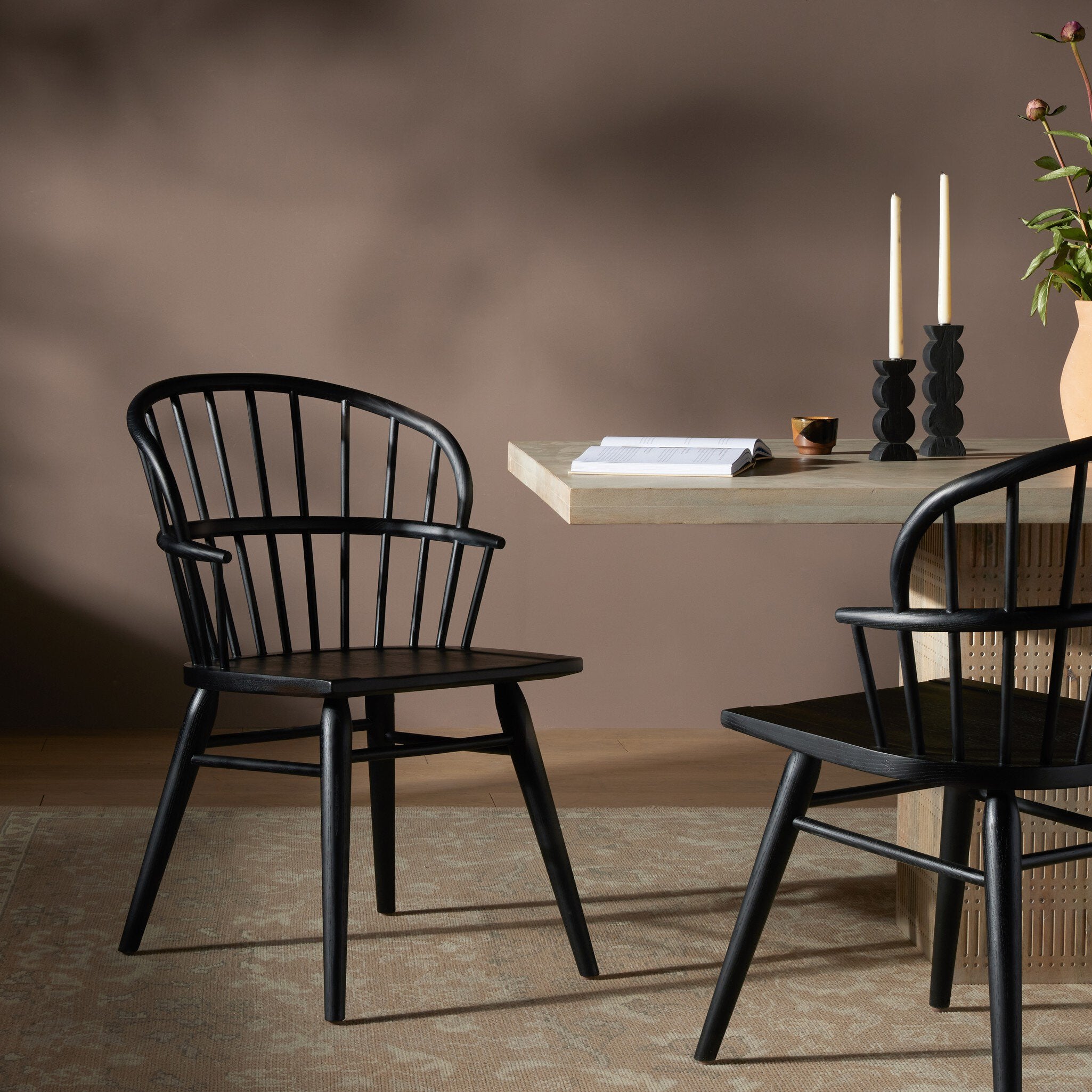 Two black dining chairs in a room with a dining table and candles. | Wildwood Home Co.