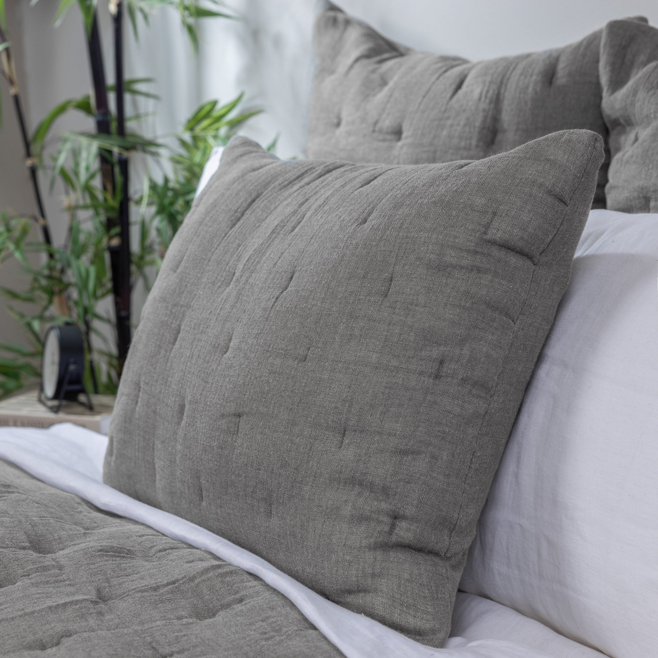 Styled bed with gray textured pillows and matching grey quilt with white sheets detailing material and texture. | Wildwood Home Co.