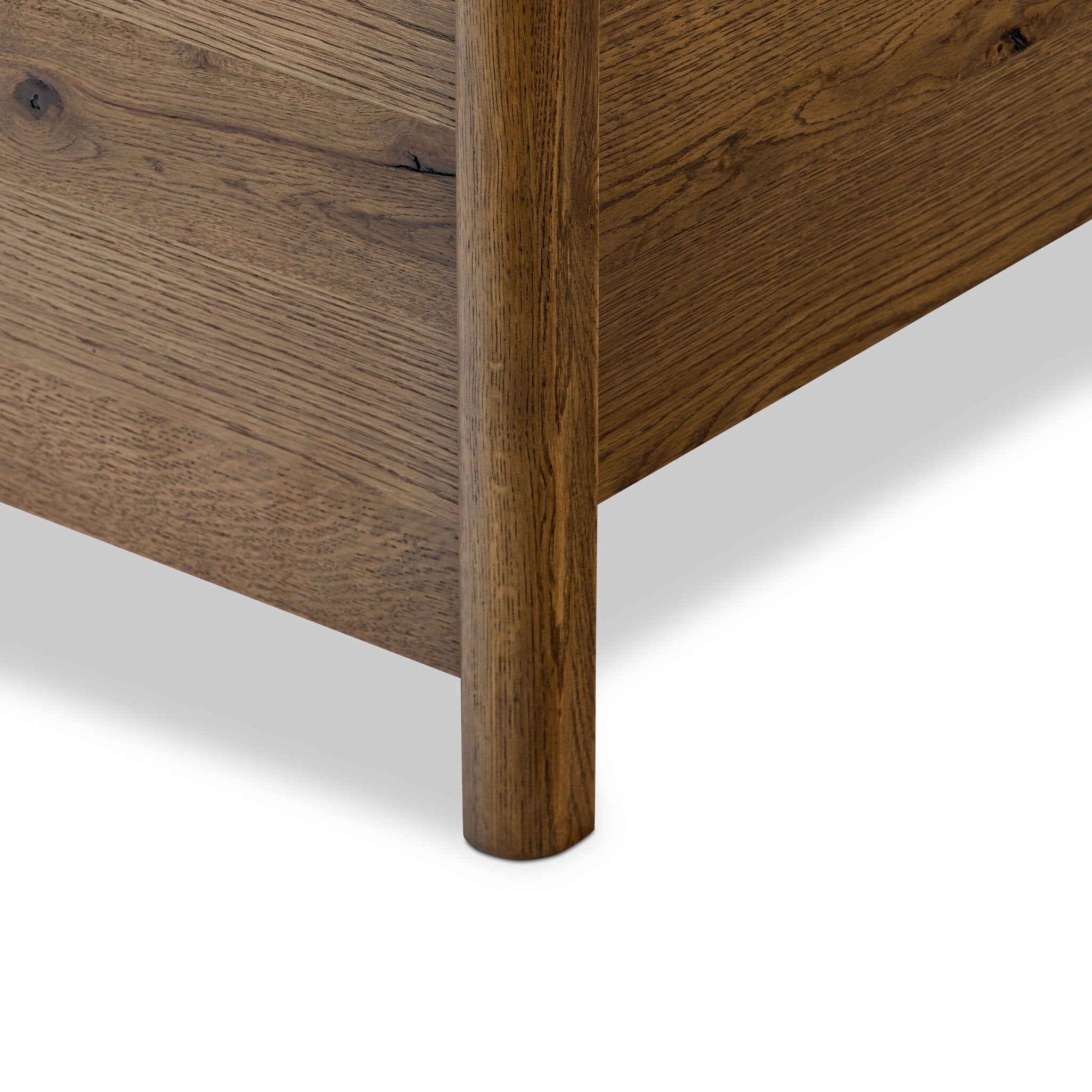 Close up of a heritage-inspired oak bed featuring soft curves, linen upholstered headboard, and white bedding on a white background.