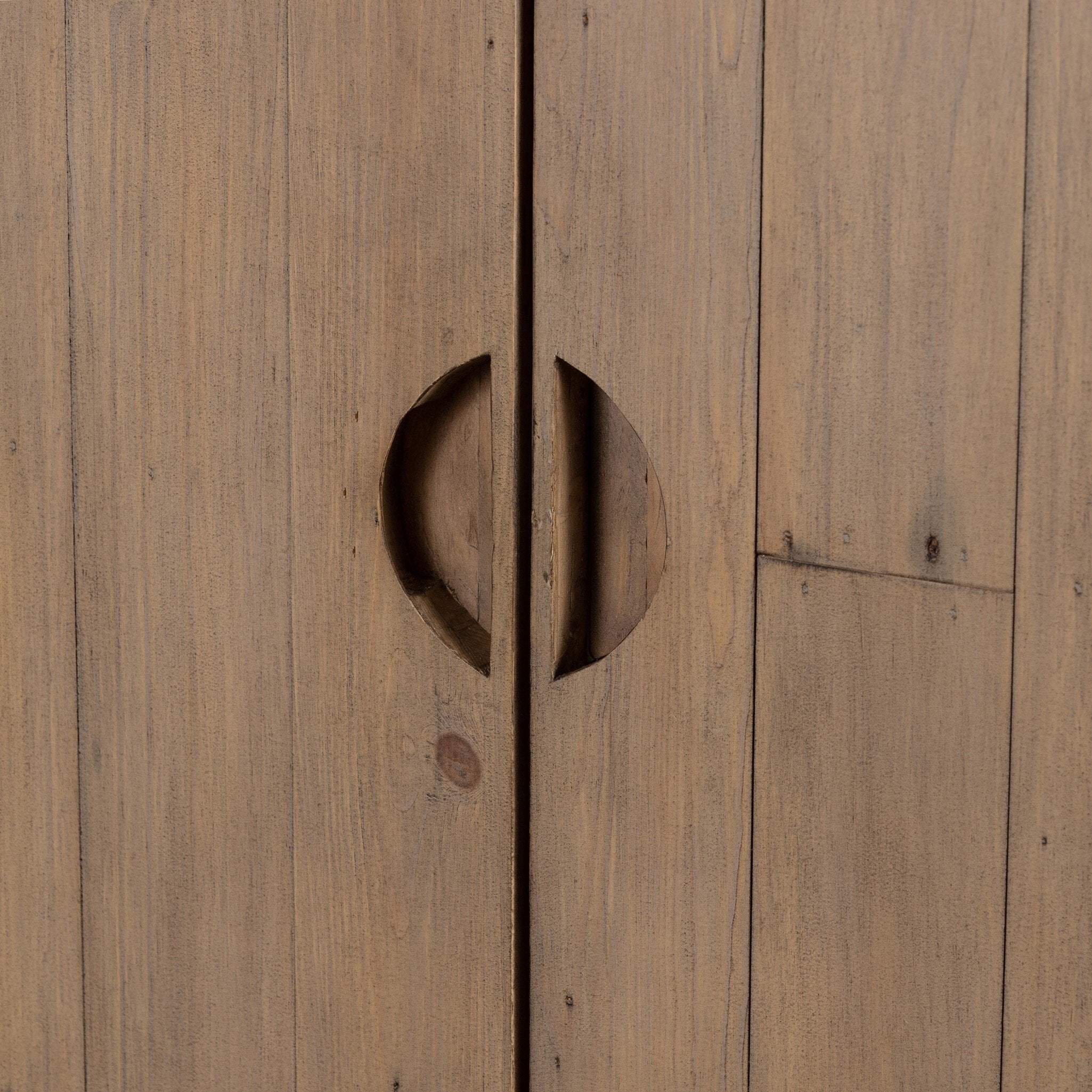 Close up of the handles of a a wooden cabinet with two doors and rounded corners on a white background.