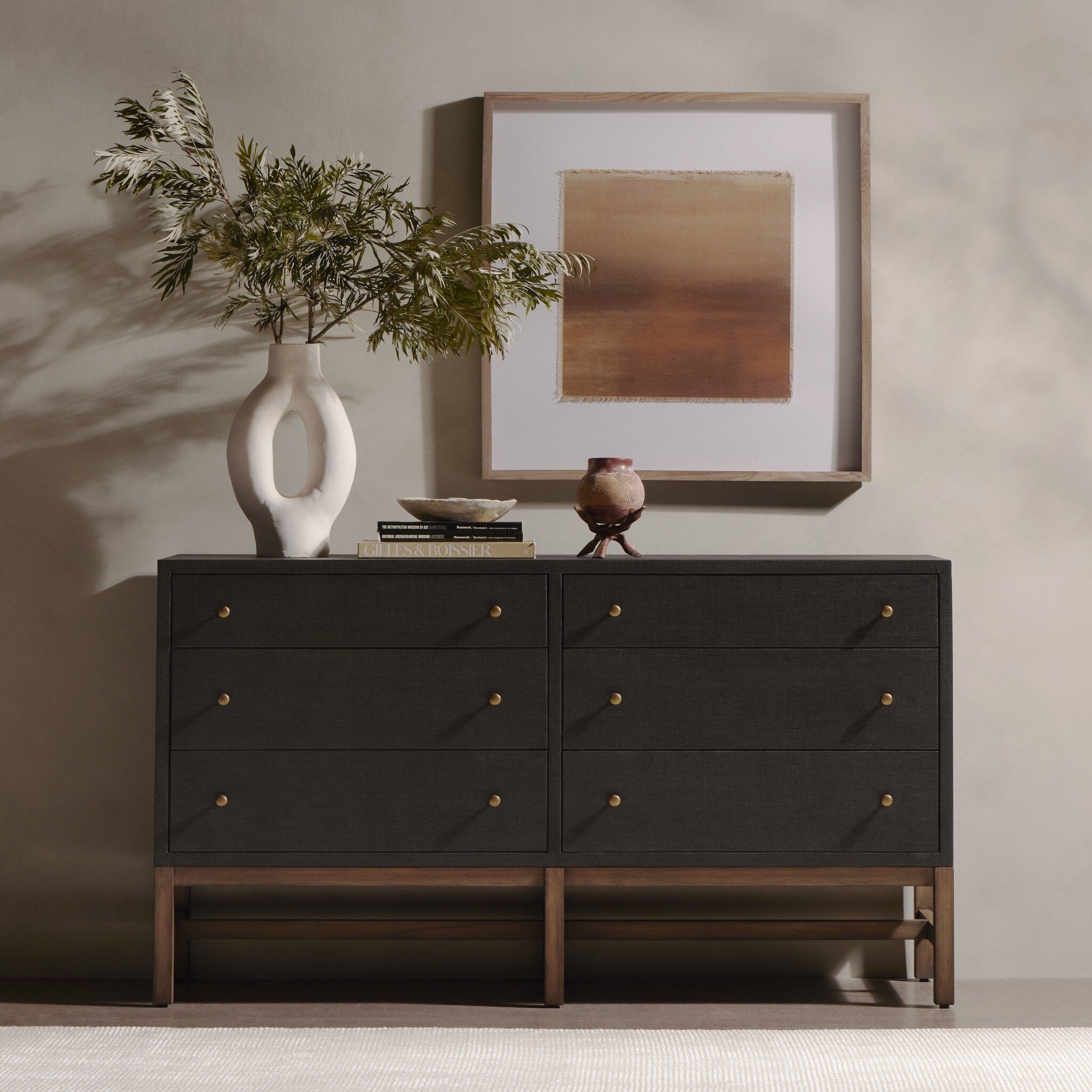 Dark wooden dresser with decorative items including a vase and framed artwork in a room. | Wildwood Home Co.