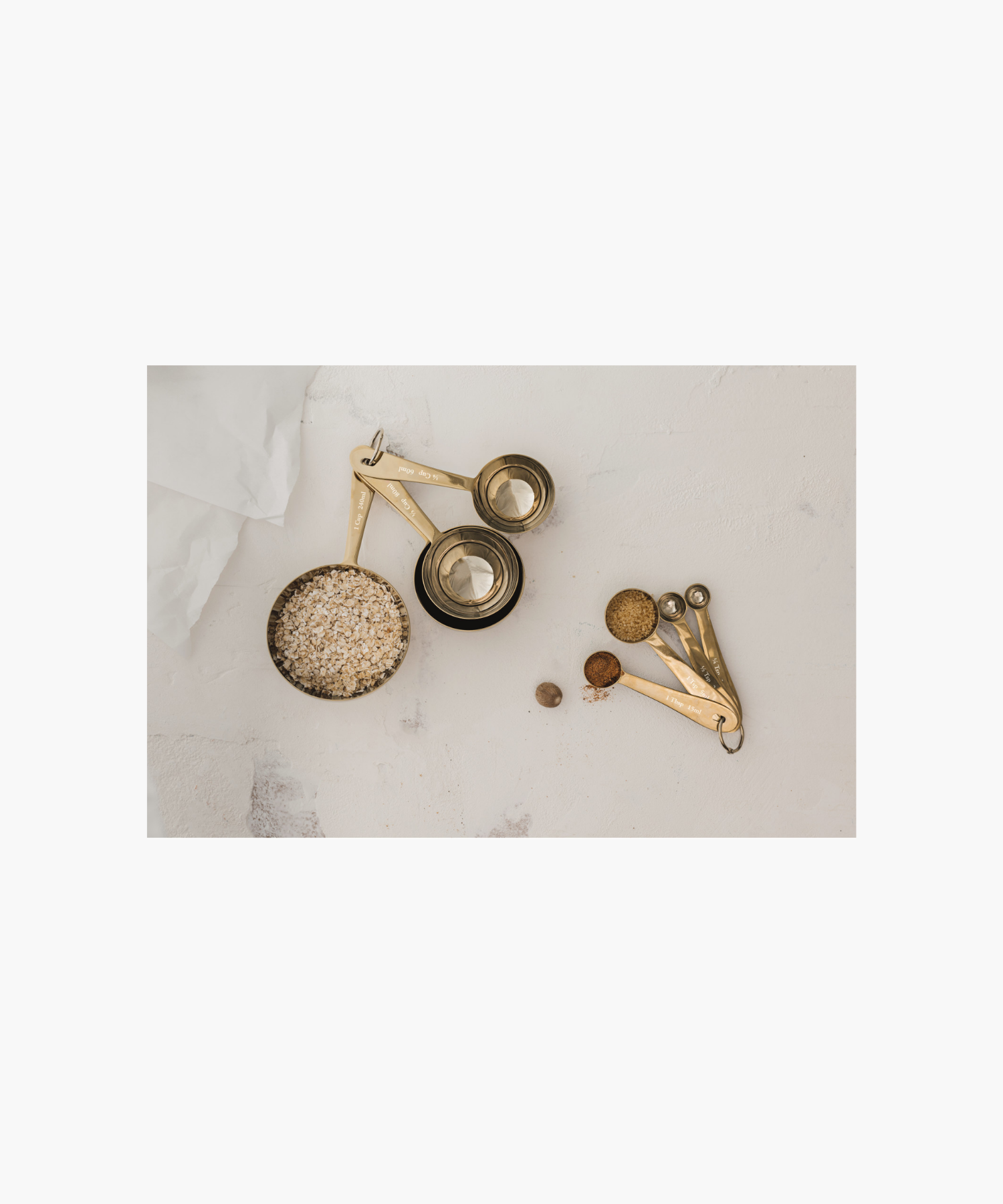 Four nested gold measuring spoons are attached by a metal ring, labeled with measurements styled with matching gold measuring cups. | Wildwood Home Co.