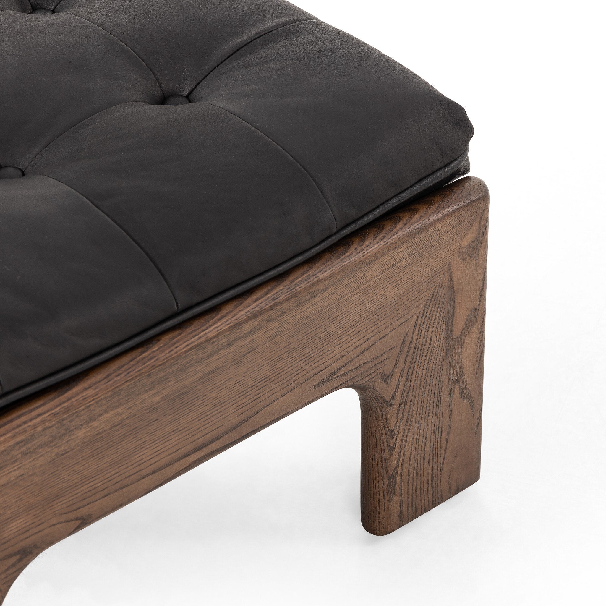Close-up of a wooden ottoman with a black cushion on a white background.