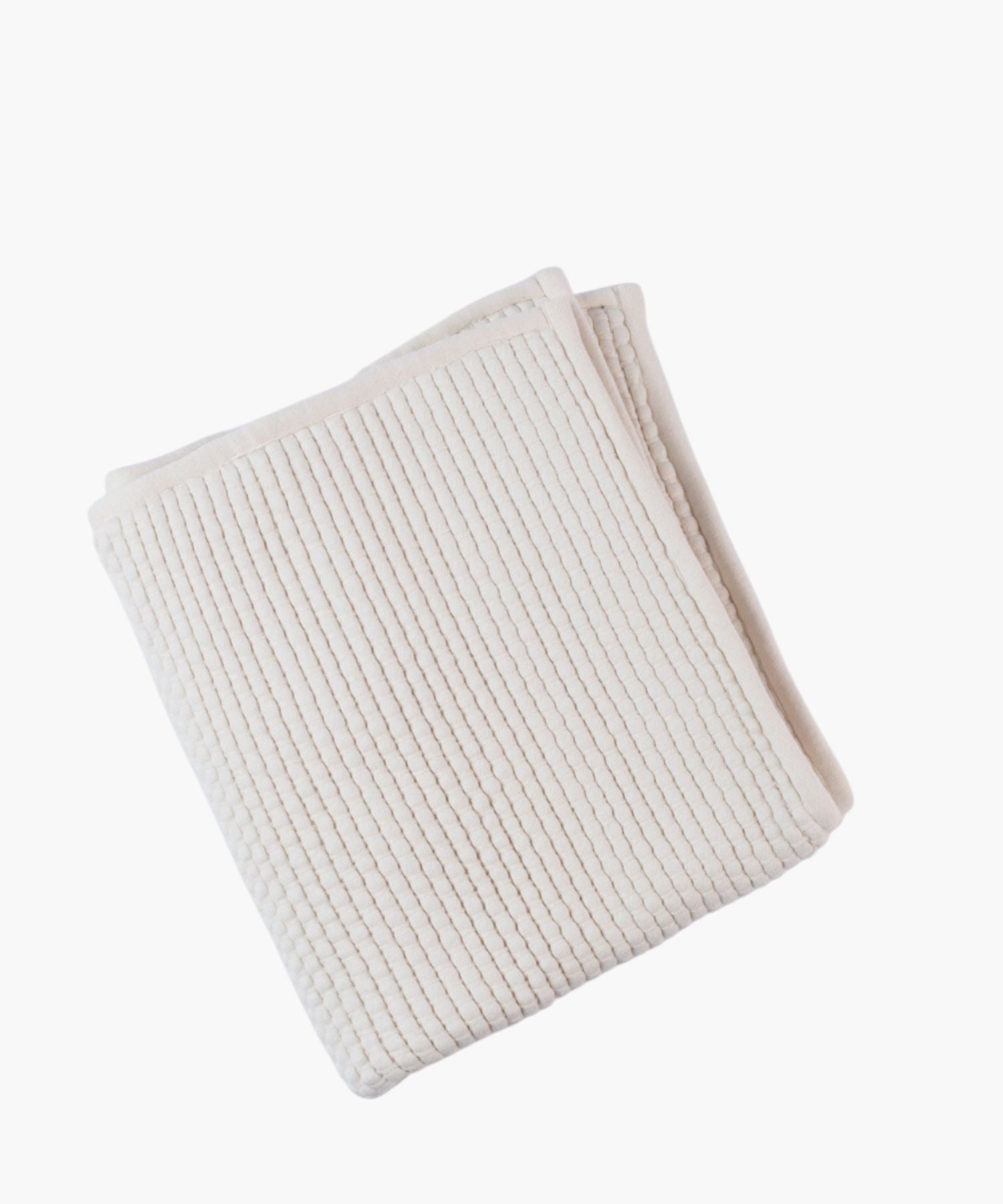 Folded ivory coverlet on a white background highlighting quilted or woven texture and soft, tonal color. | Wildwood Home Co.