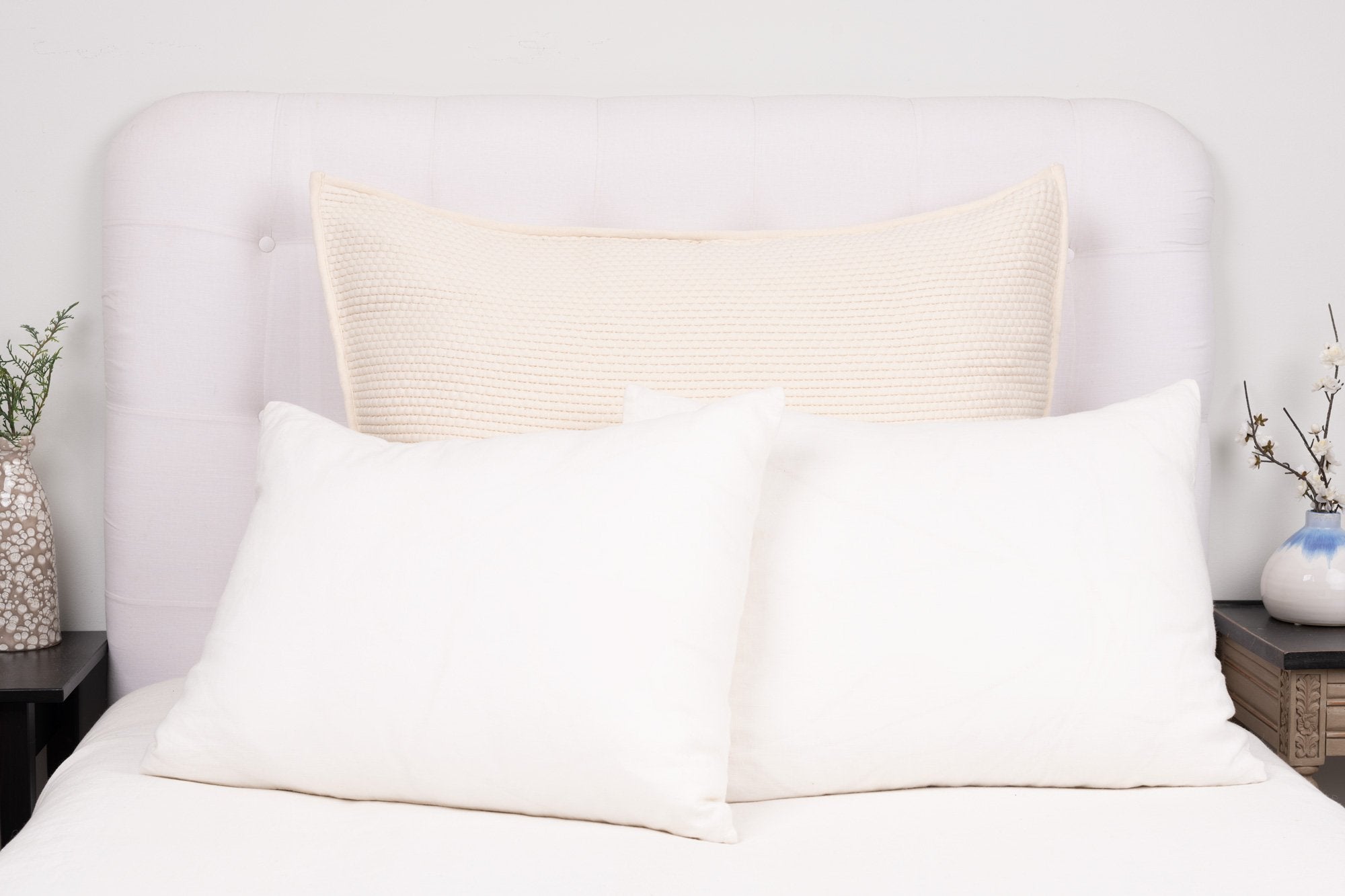 Large ivory pillow cover styled on a white bed showing knife edge or flange detailing, fabric texture, and muted palette. | Wildwood Home Co.