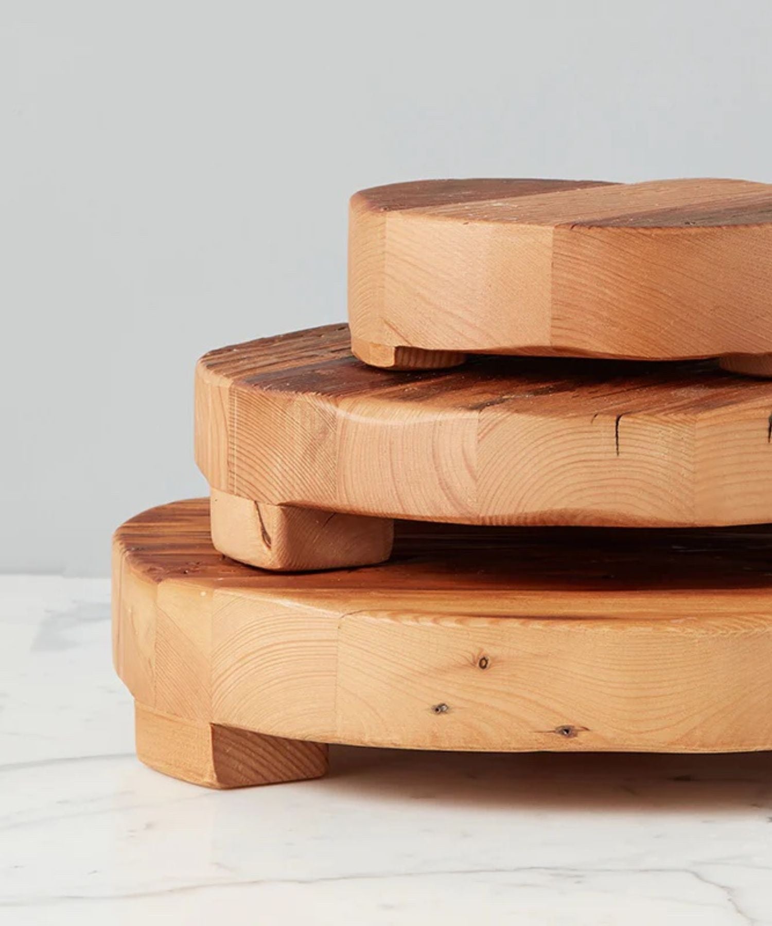 Round wooden pedestal or trivet made of smooth, natural wood with subtle grain patterns, supported by small rounded legs in 2 sizes. Conveys rustic and minimalist elegance. | Wildwood Home Co.