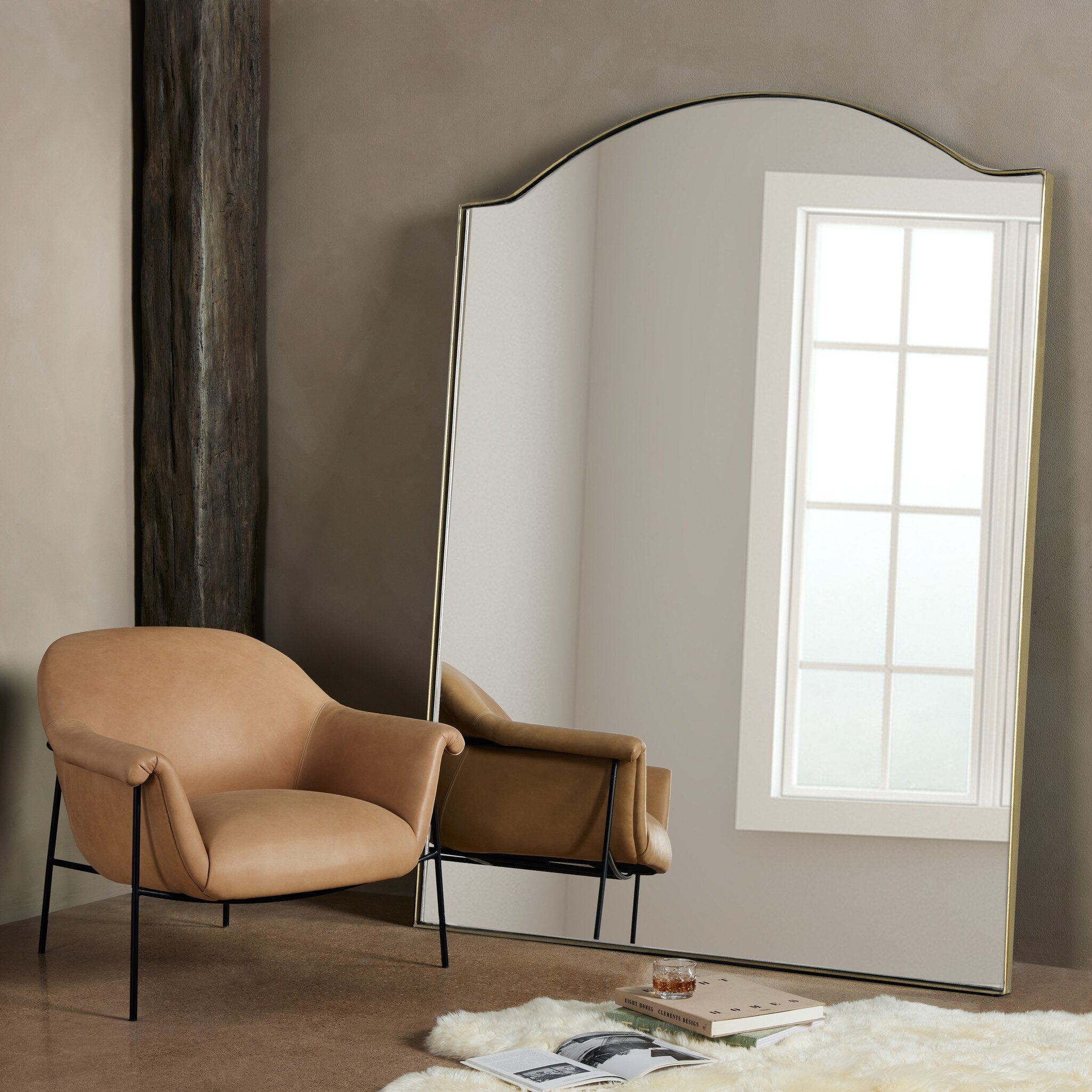 Beige armchair next to a large floor mirror in a room with a window. | Wildwood Home Co.