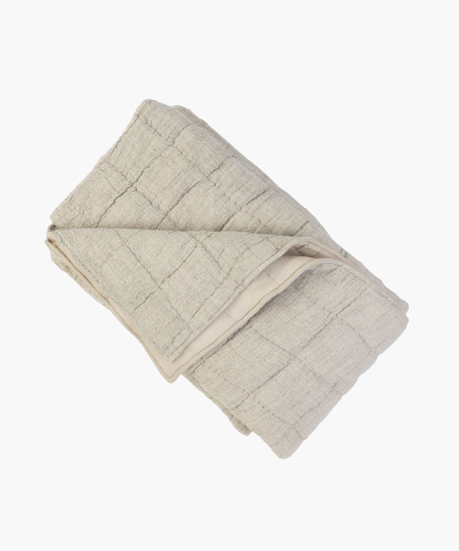 Folded beige cotton-linen blend quilt on a white background showing its puckered texture and hand-stitched block pattern. | Wildwood Home Co.