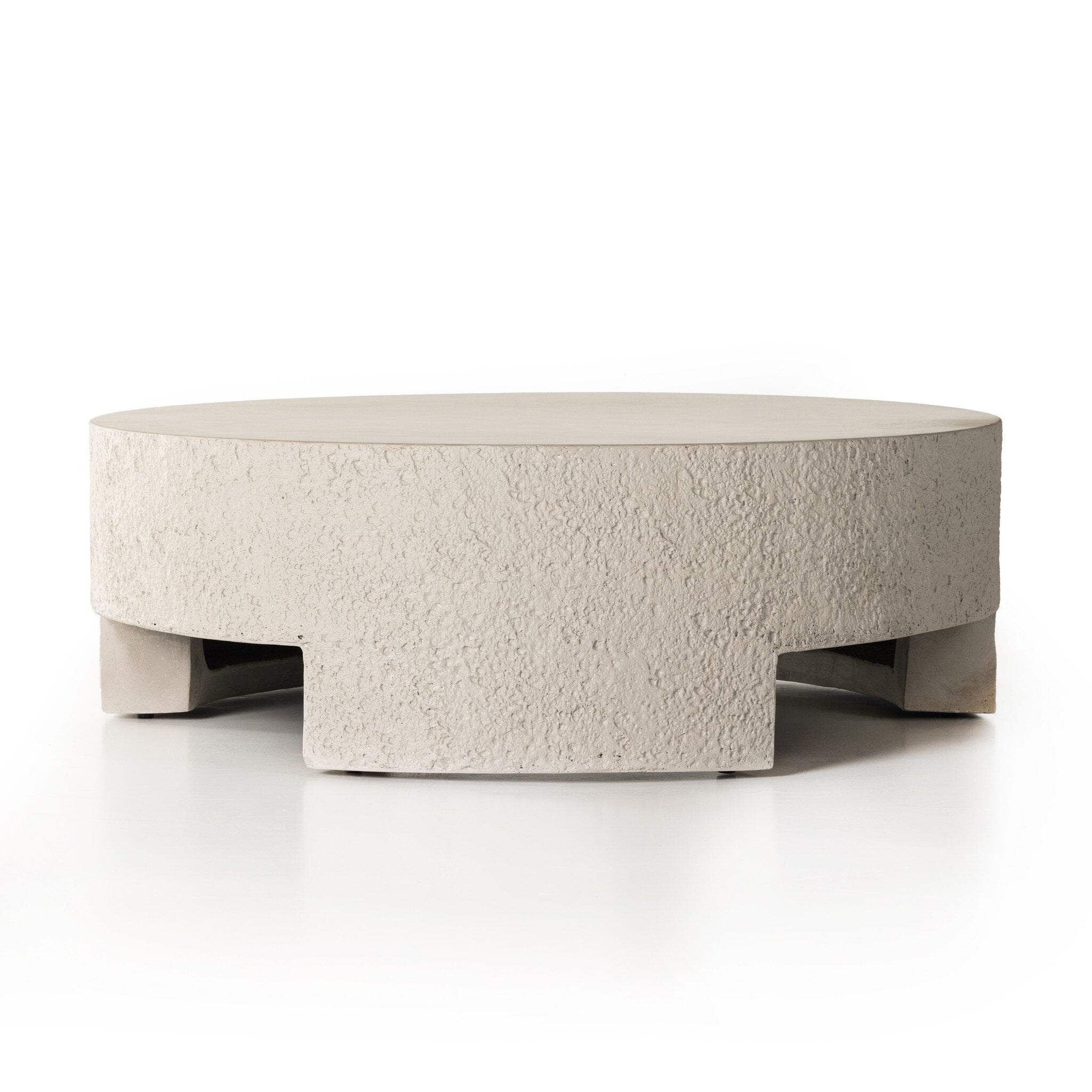 A round pumice concrete coffee table with a smooth top and cutout legs. | Wildwood Home Co.