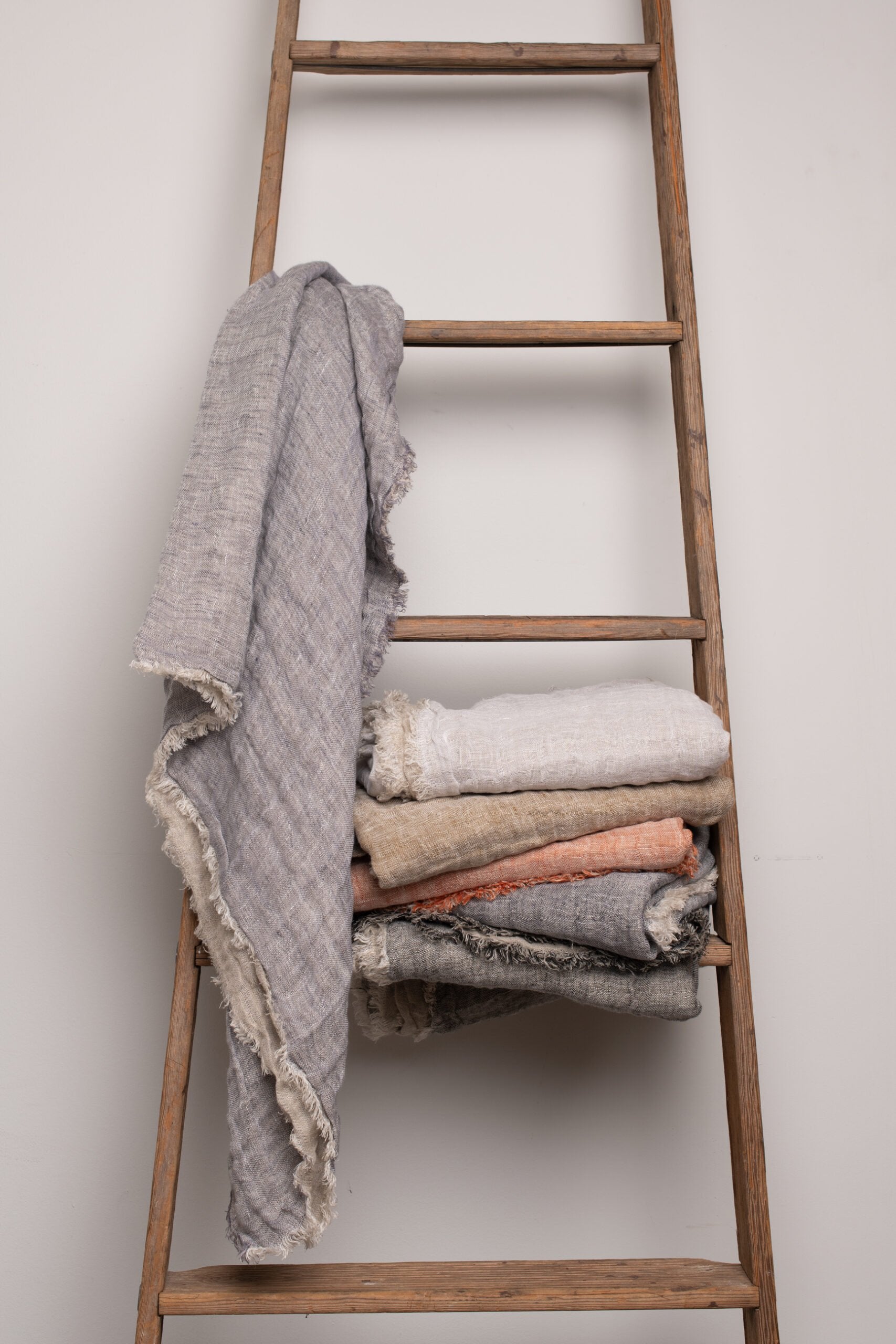 Kent Super Throws styled on a rustic wooden ladder in assorted colors, showcasing its eyelash edge and casual drape.