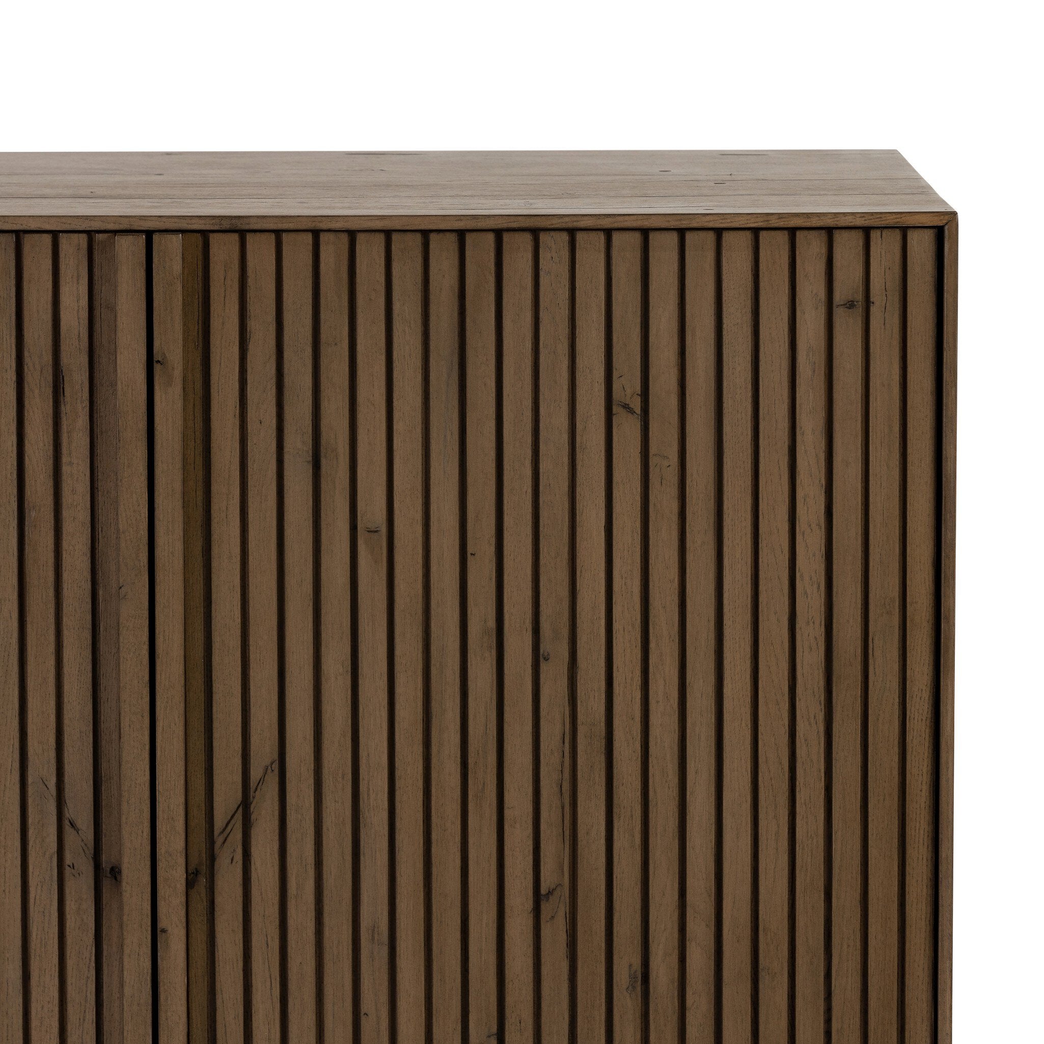 Close up of a wooden sideboard with vertical reeding on a white background.