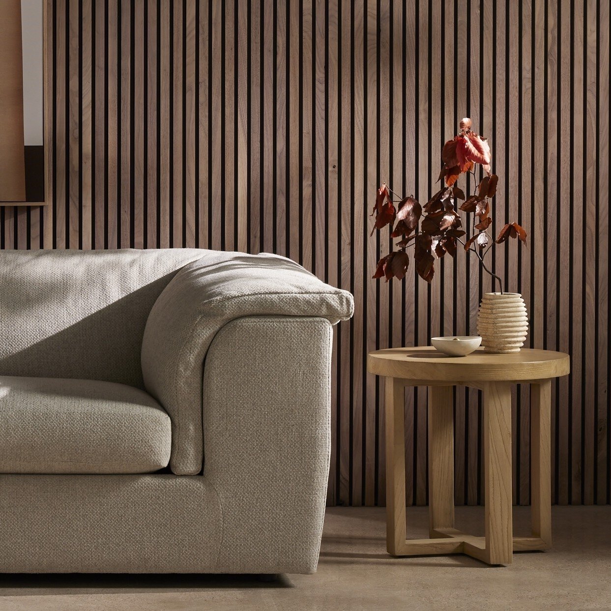 Beige sofa in a room with wooden side table and decorative plant against striped wall. | Wildwood Home Co.