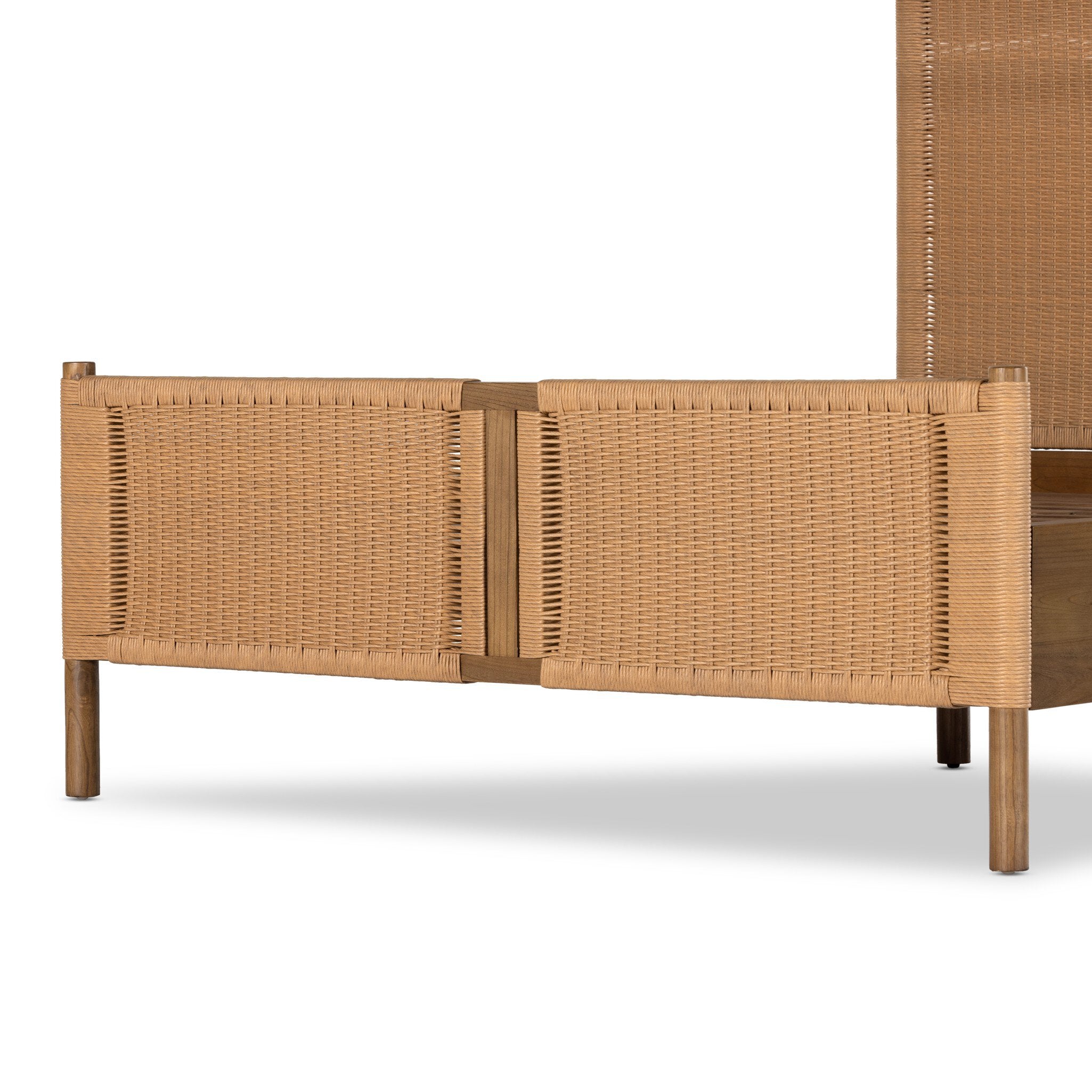 Close up of a wicker bed with white bedding on a white background.