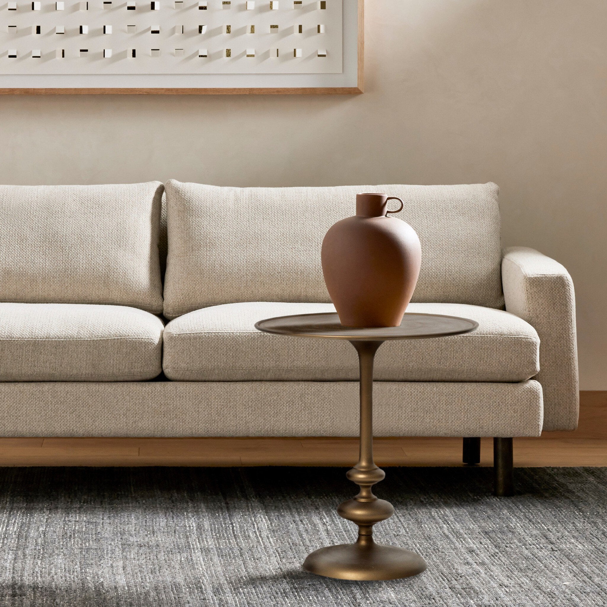 Beige sofa with a bronze side table and decorative vase in a living room setting. | Wildwood Home Co.