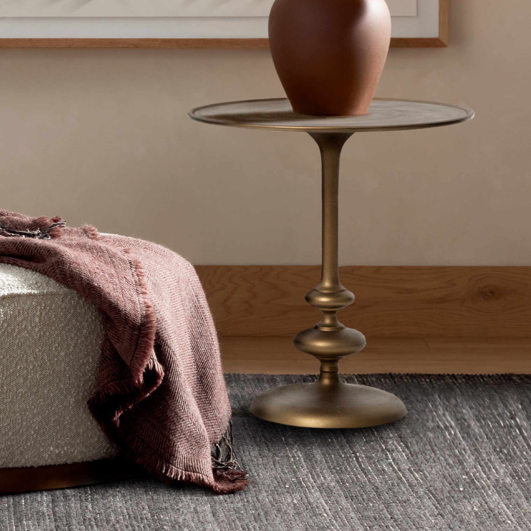 Brass side table with a vase on a gray carpeted floor.