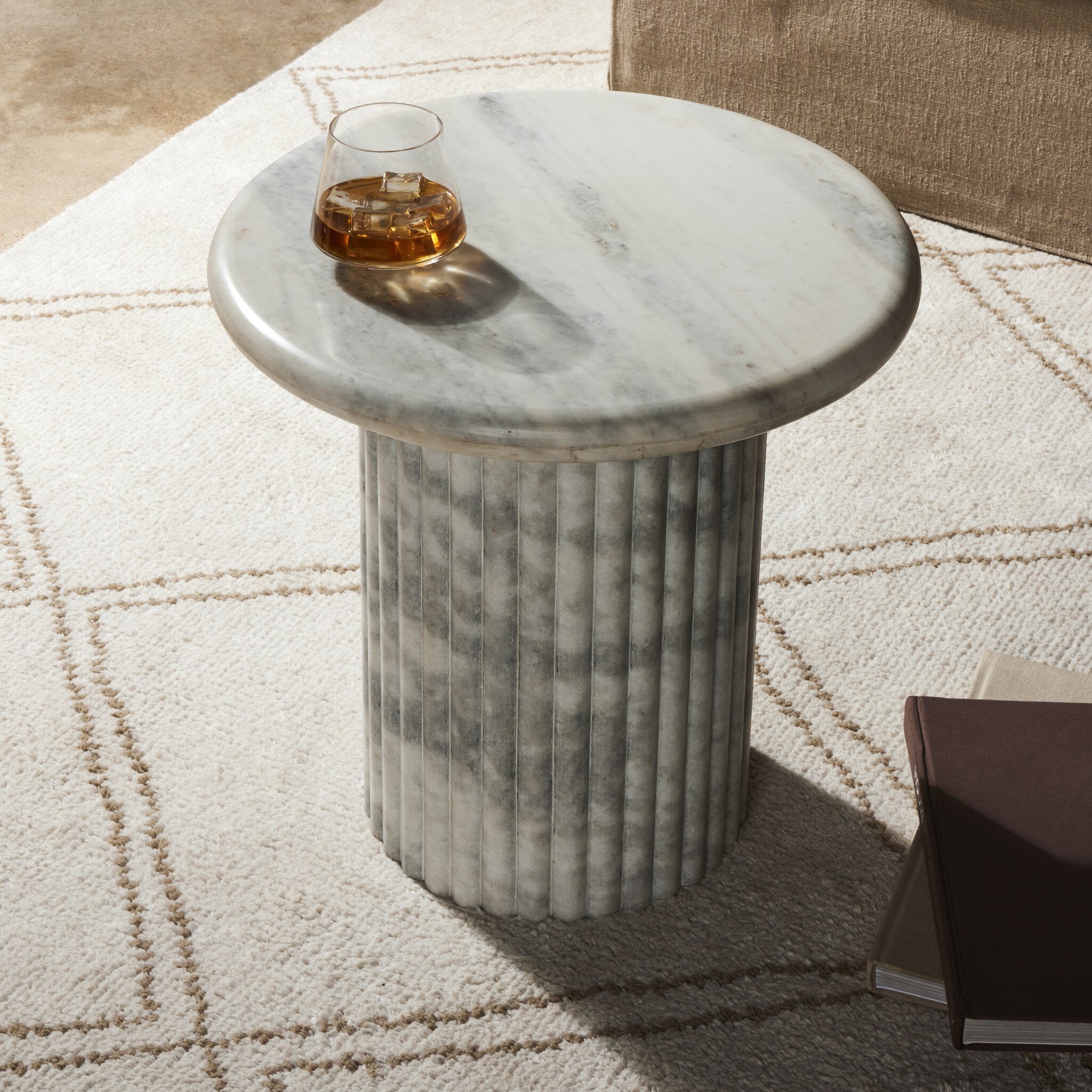 Marble end table with a glass of whiskey on a patterned rug. | Wildwood Home Co.
