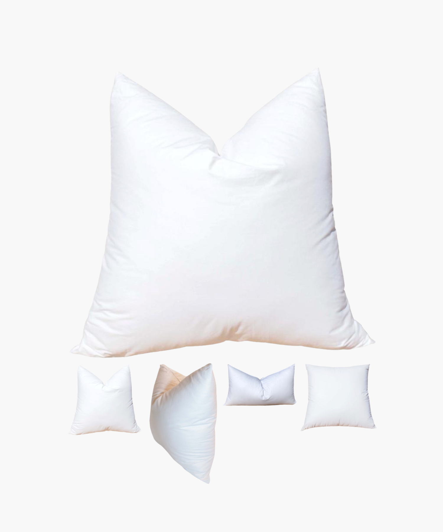 A large white pillow insert centrally displayed, surrounded by four smaller pillow inserts of varying shapes against a plain background, conveying softness and comfort. | Wildwood Home Co.