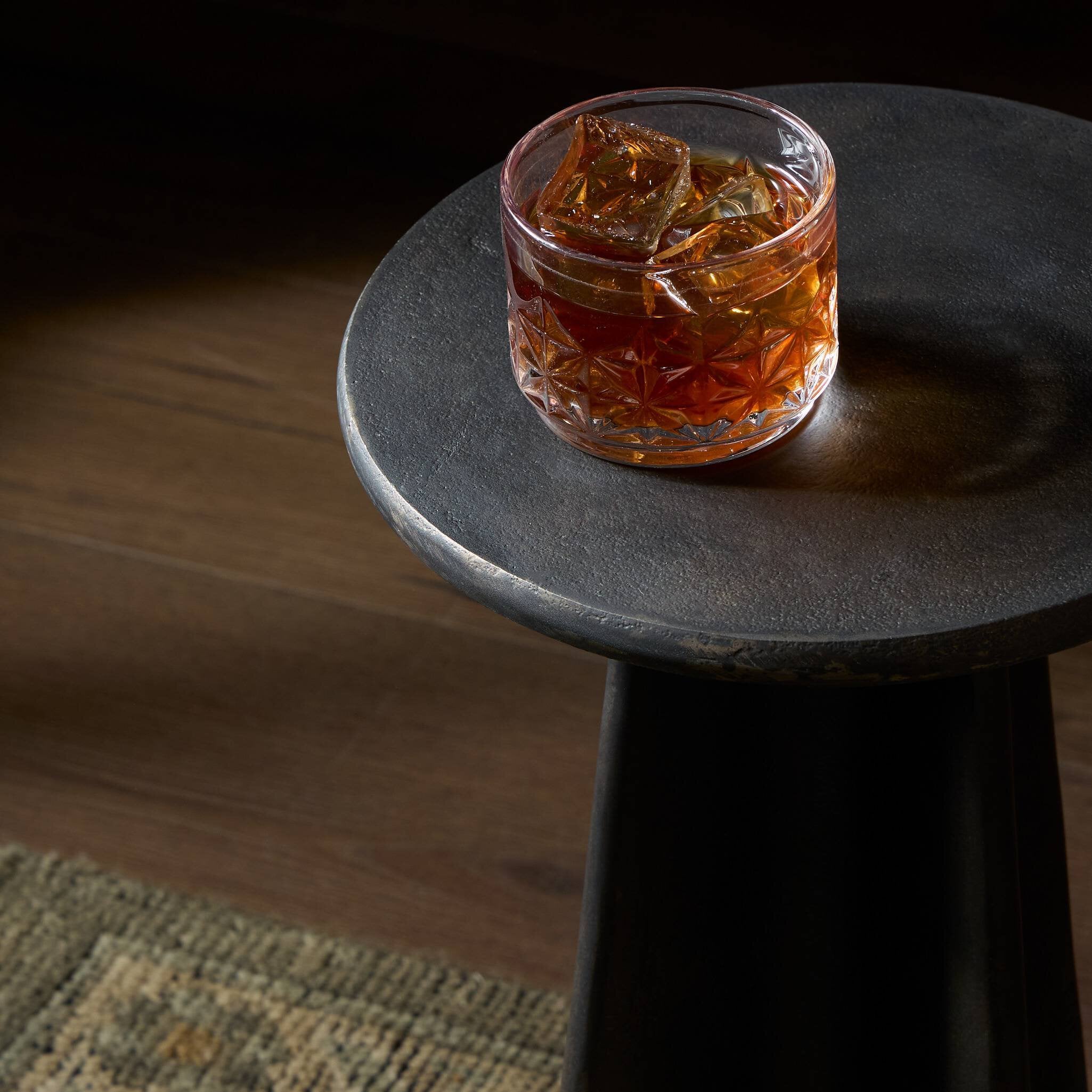 Glass of whiskey with ice on a dark stone surface