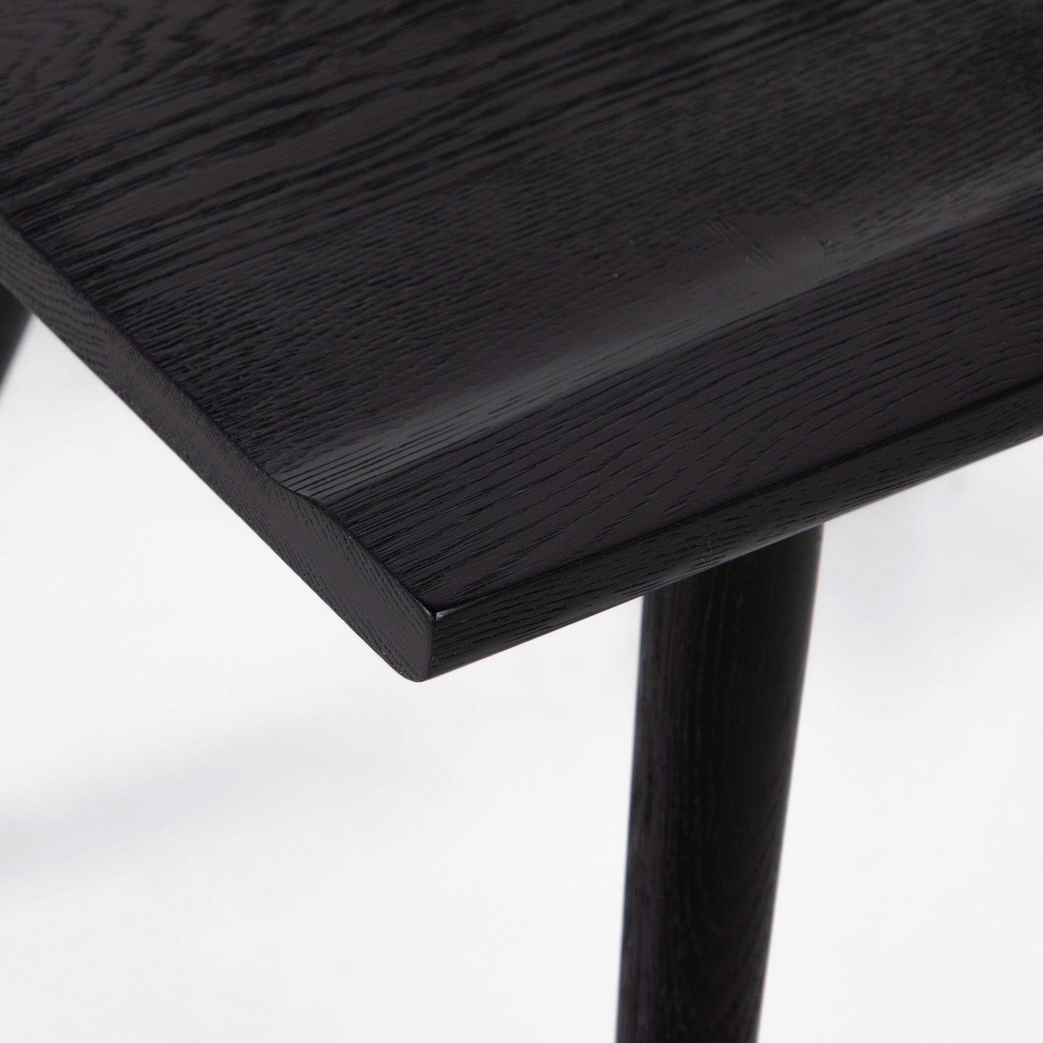 Close up of a black wooden dining chair on a white background.