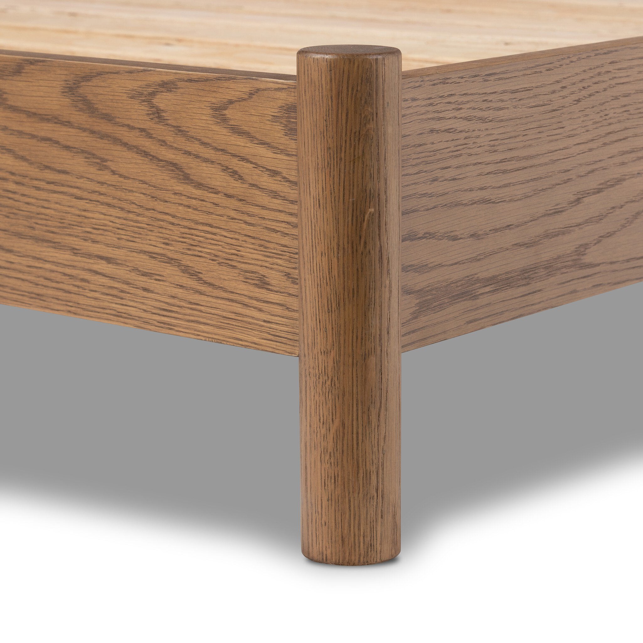 Close up of a wooden bed with upholstered headboard and white bedding on a white background.