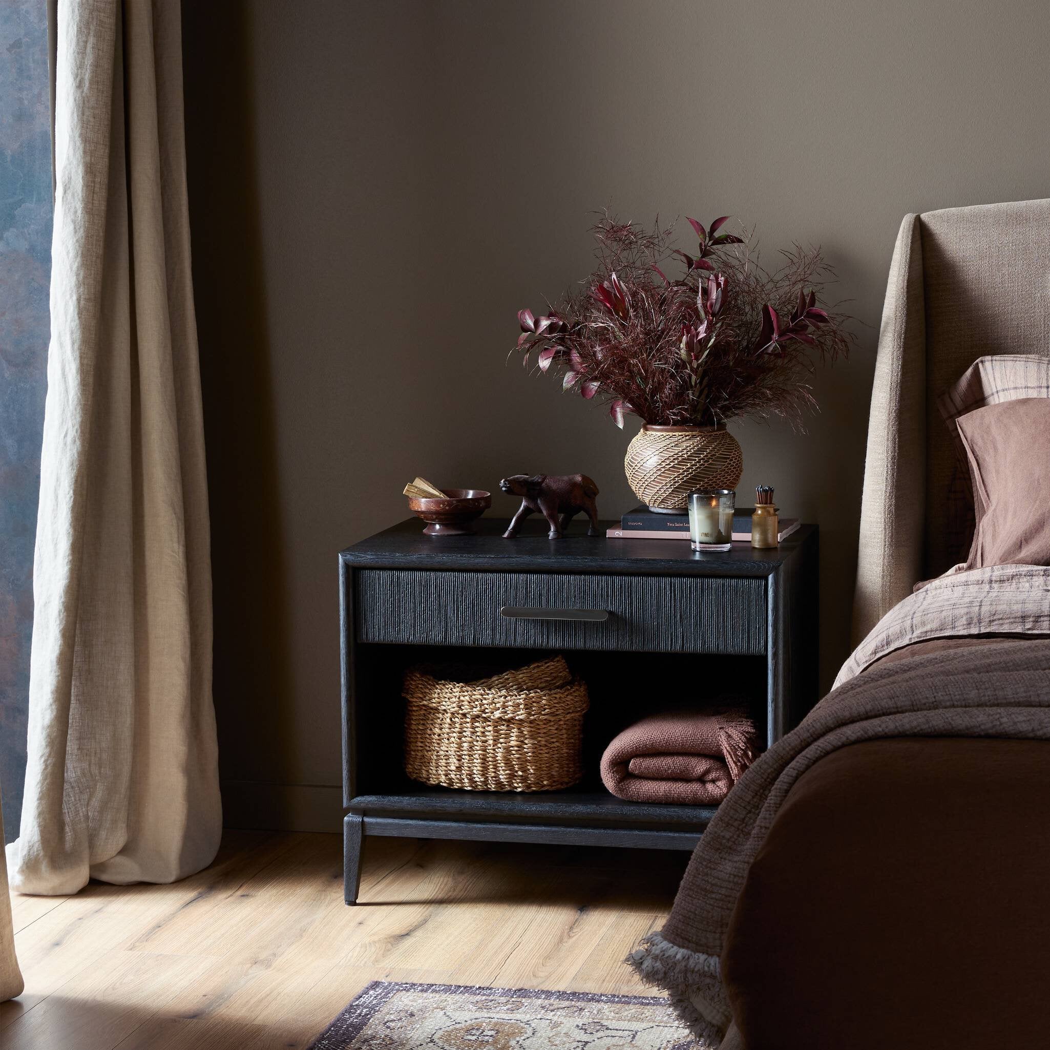 Nightstand with decorative items next to a bed in a bedroom setting. | Wildwood Home Co.