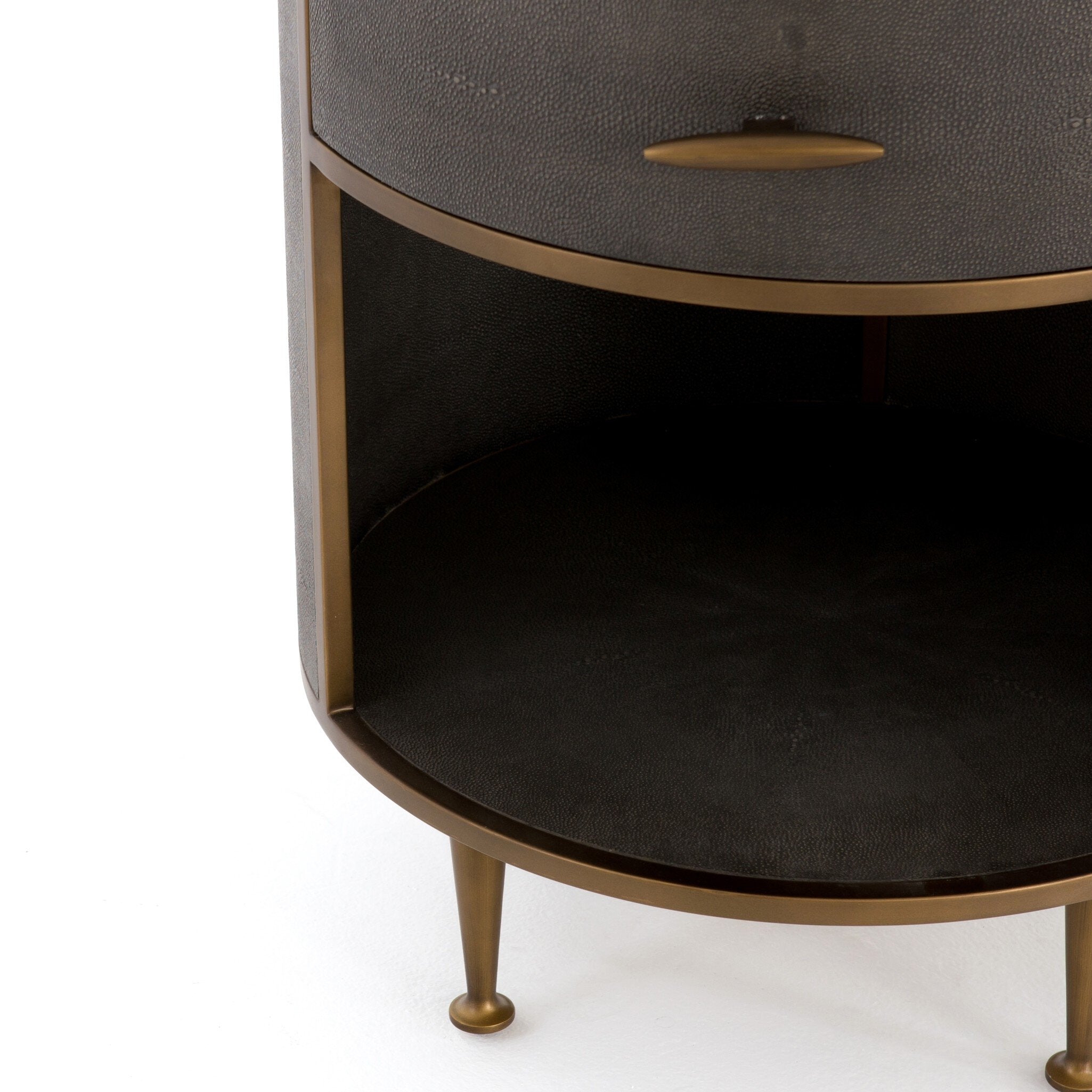 A close up of a round side table with a drawer and brass legs on a white background.