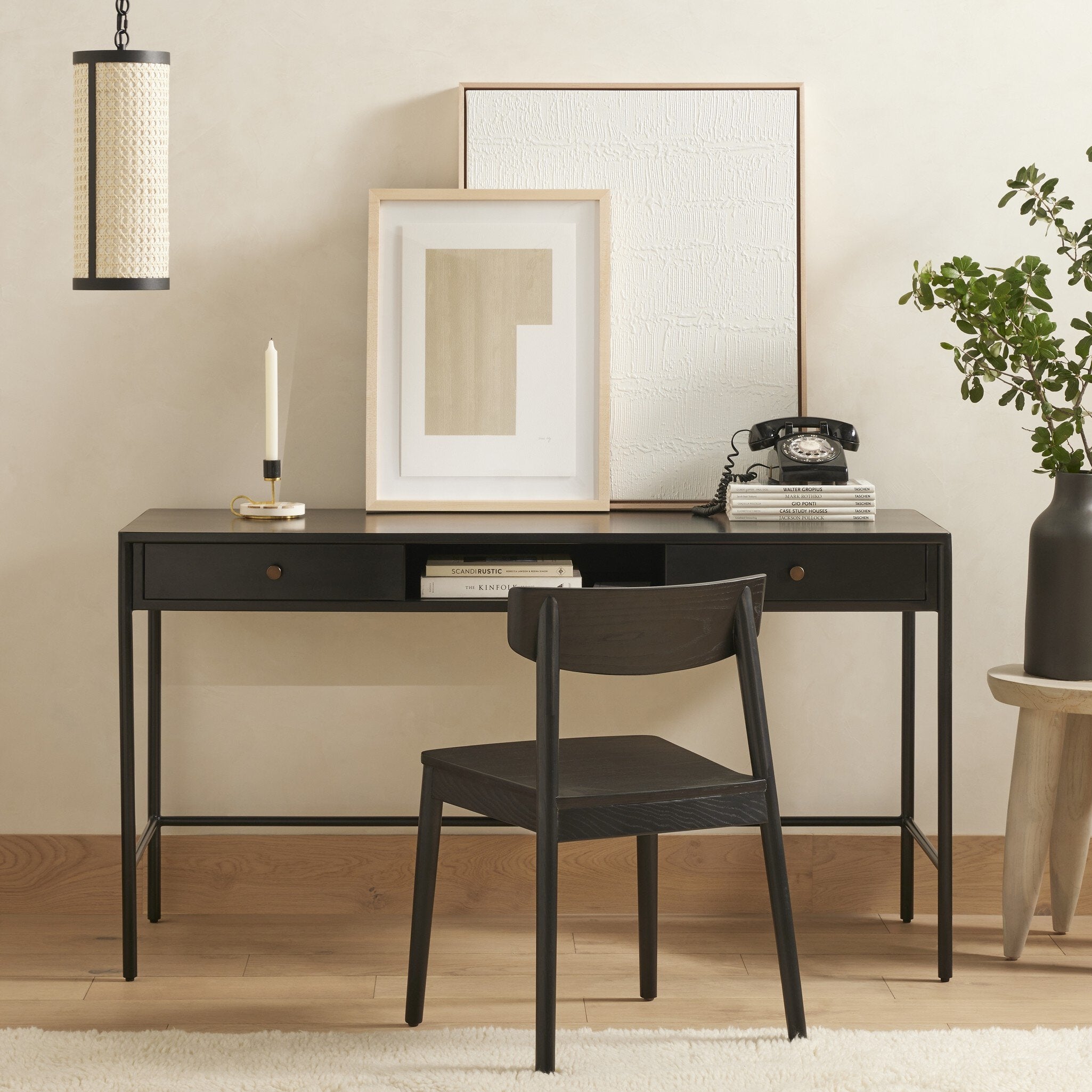 Black desk with chair, framed art, and decorative items in a room. | Wildwood Home Co.