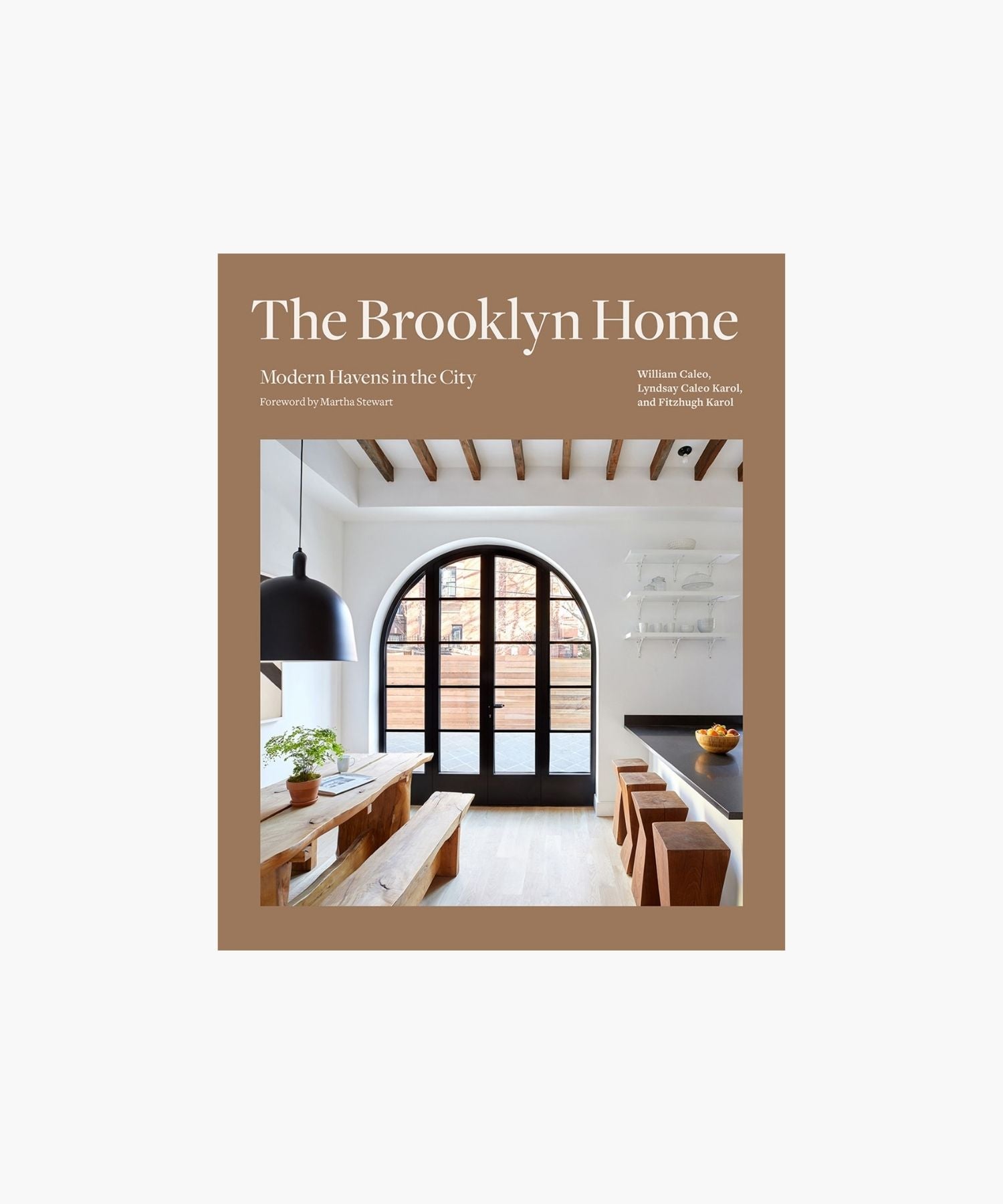 The cover of the book "The Brooklyn Home" shows a modern dining room with exposed beams, a large arched window, wooden furniture, and a plant. Minimalist and inviting. | Wildwood Home Co.
