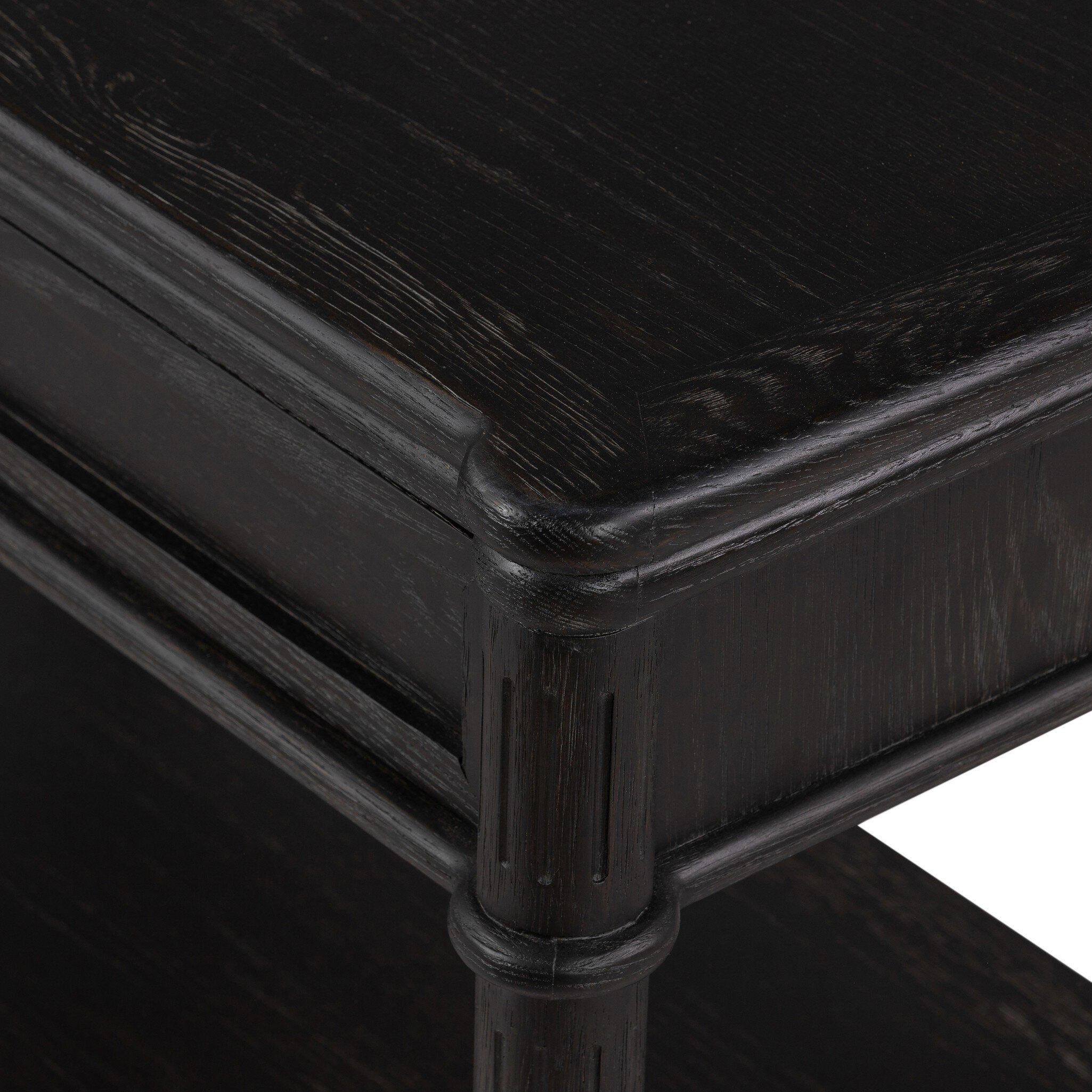 Close up of a distressed black oak nightstand with a drawer and a shelf on a white background.