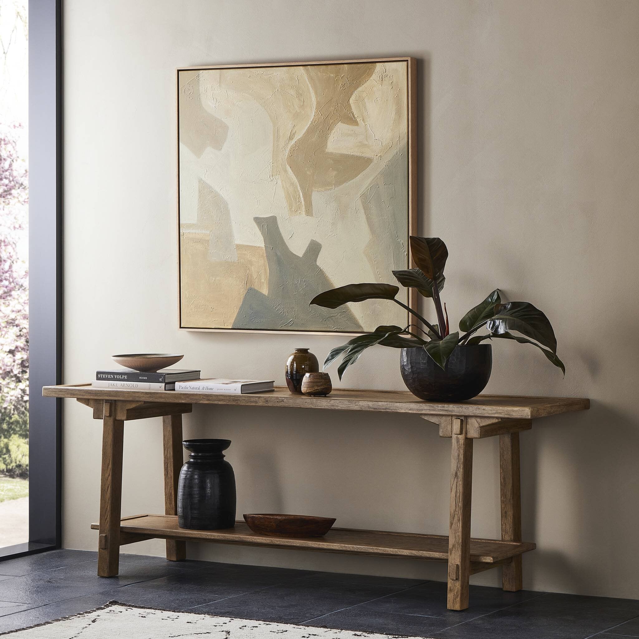 Wooden console table with decorative items and a large abstract painting in a room. | Wildwood Home Co.