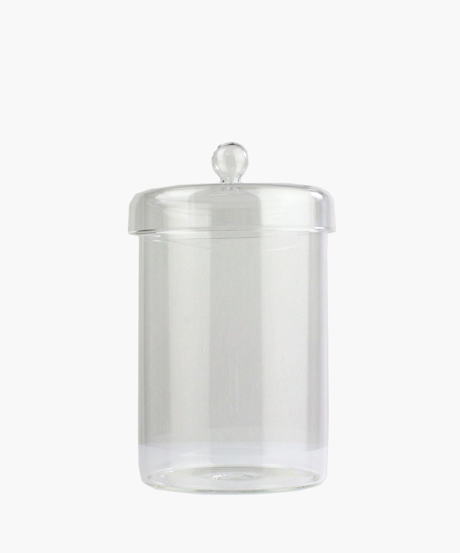 A clear glass jar with a round lid and a knob handle is centered on a plain white background. The jar is empty, conveying simplicity and elegance. | Wildwood Home Co.