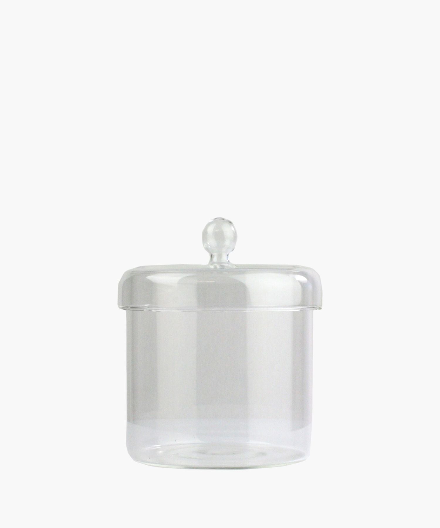 A clear glass jar with a round lid and a knob handle is centered on a plain white background. The jar is empty, conveying simplicity and elegance. | Wildwood Home Co.
